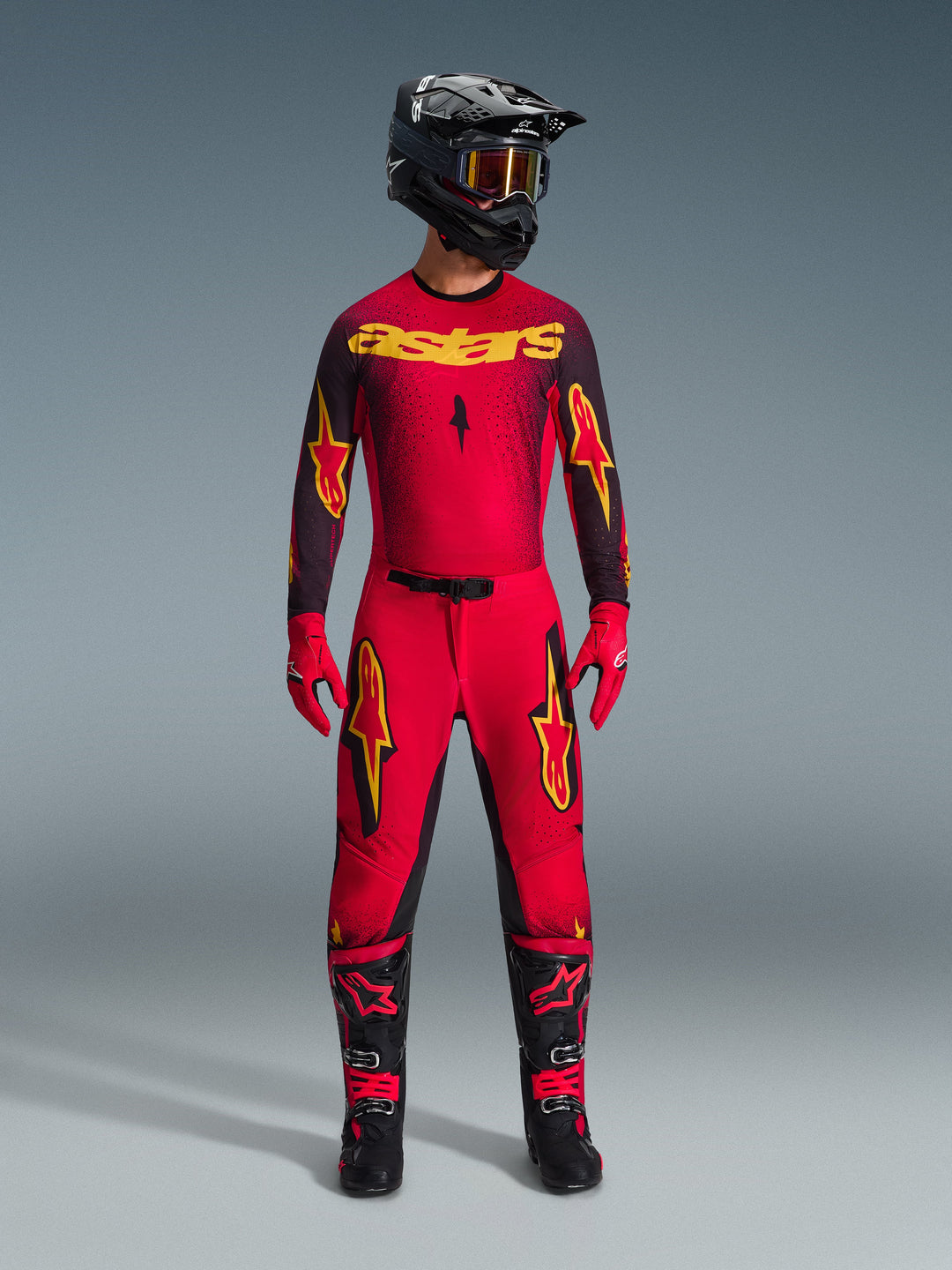 Alpinestars 2026 Supertech Scenz Gear Set, conjunto completo de motocross en rojo y negro con gráficos amarillos, con jersey de nivel profesional y pantalones a juego, usado con casco negro, guantes rojos y botas de competición negras, equipo de alto rendimiento para competición todoterreno