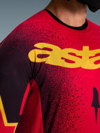 Alpinestars 2026 Supertech Scenz Jersey, jersey de motocross, rojo, negro y amarillo, primer plano de la zona del pecho con marca amarilla, patrón moteado negro y perforaciones cortadas con láser para ventilación.