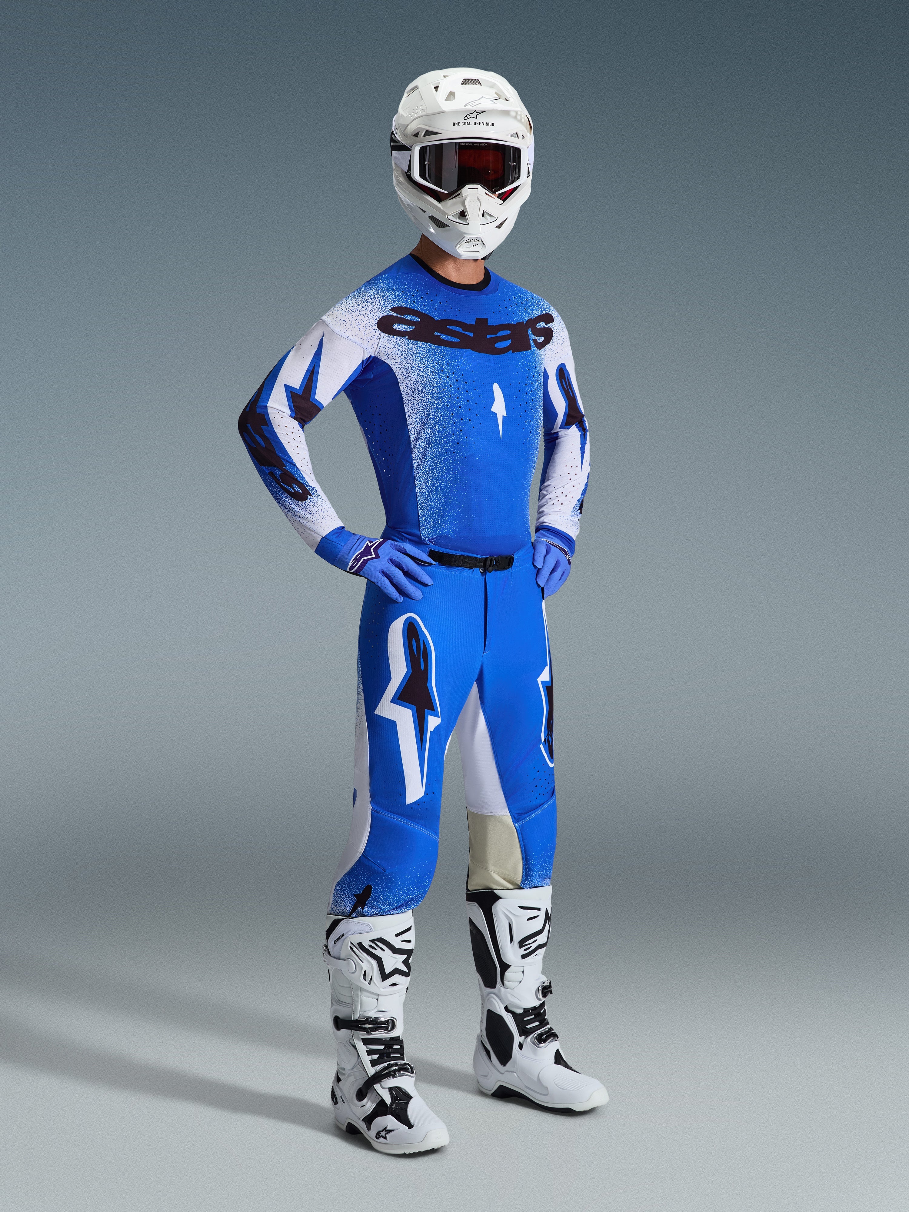 Motocross rider wearing the Alpinestars 2026 Supertech Scenz Gear Set in Ucla Blue and White, featuring a pro-level jersey with 'astars' branding, matching performance pants, white helmet, dark goggles, and white and black off-road boots.