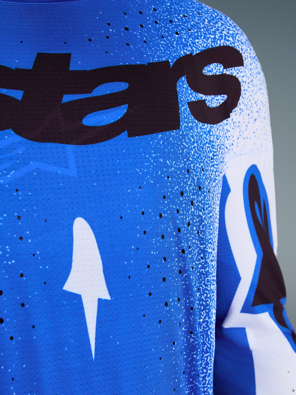 Alpinestars 2026 Supertech Scenz Jersey, close-up of Ucla Blue and White design, featuring laser-cut perforations for ventilation, black 'stars' branding, and breathable mesh fabric for professional motocross racing.