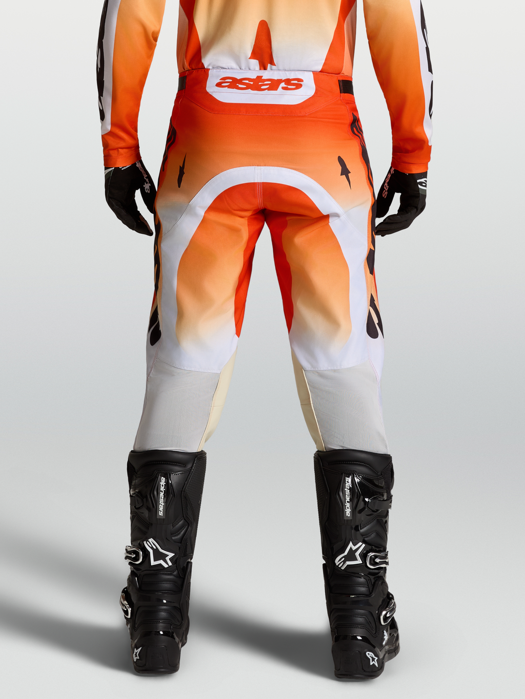 Alpinestars Pantalones Racer Amber, pantalones de motocross para hombre, rojos y blancos, vista trasera con botas negras, diseño off-road técnico