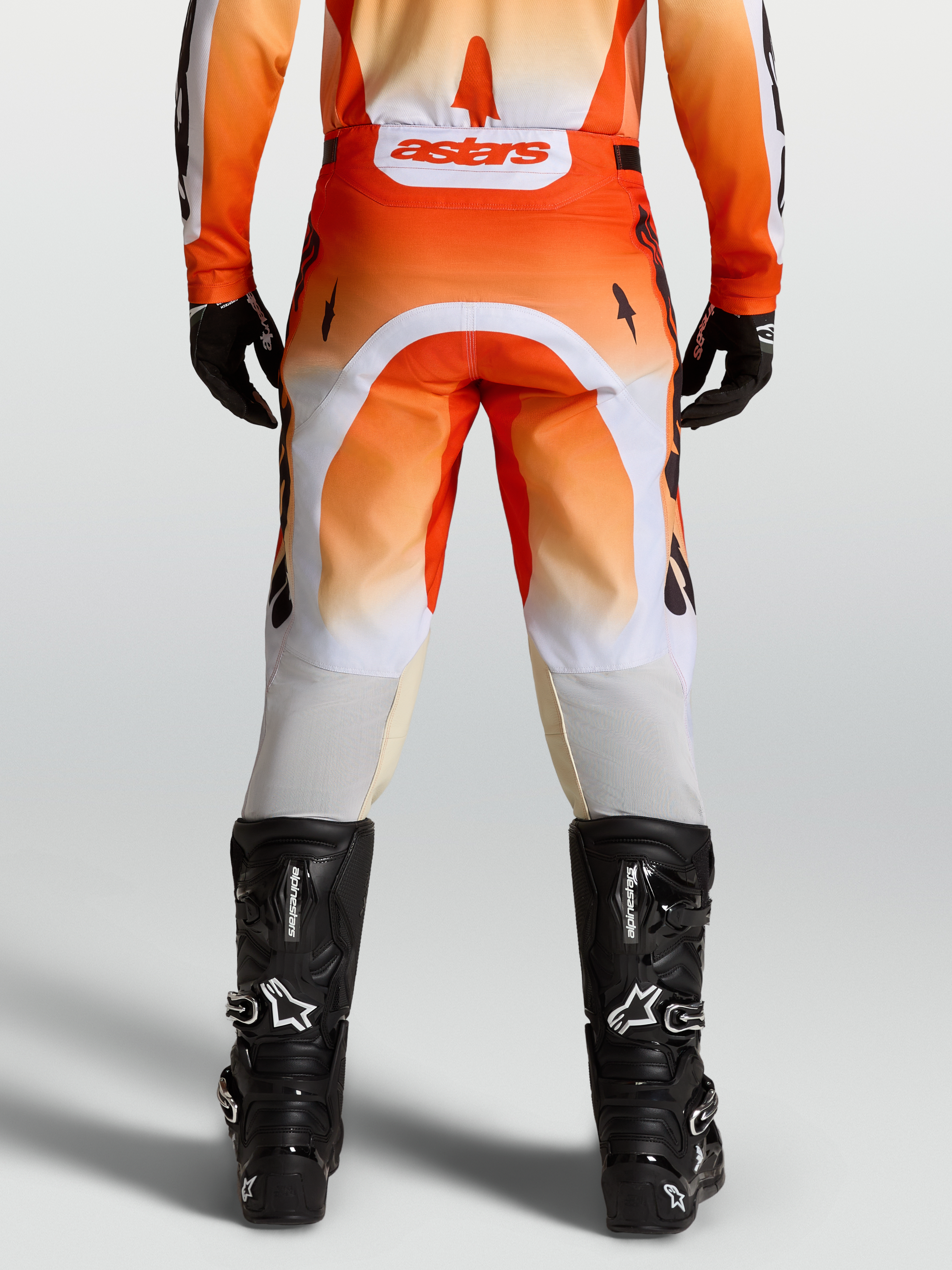Alpinestars Pantalones Racer Amber, pantalones de motocross para hombre, rojos y blancos, vista trasera con botas negras, diseño off-road técnico