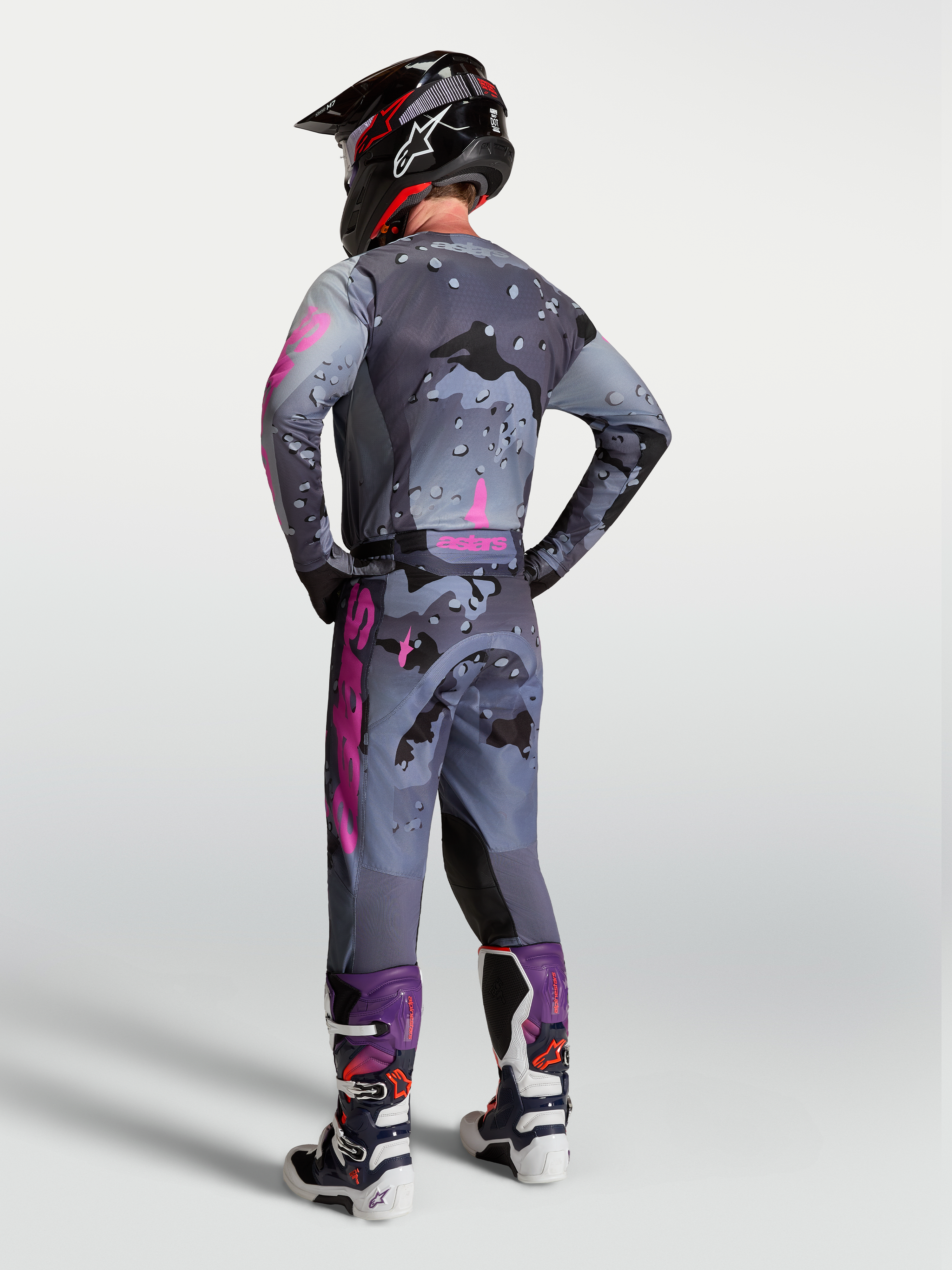 Alpinestars pantalones Racer Lone, pantalones de motocross para hombre, gris con camuflaje y morado, vista posterior en modelo con jersey y botas a juego