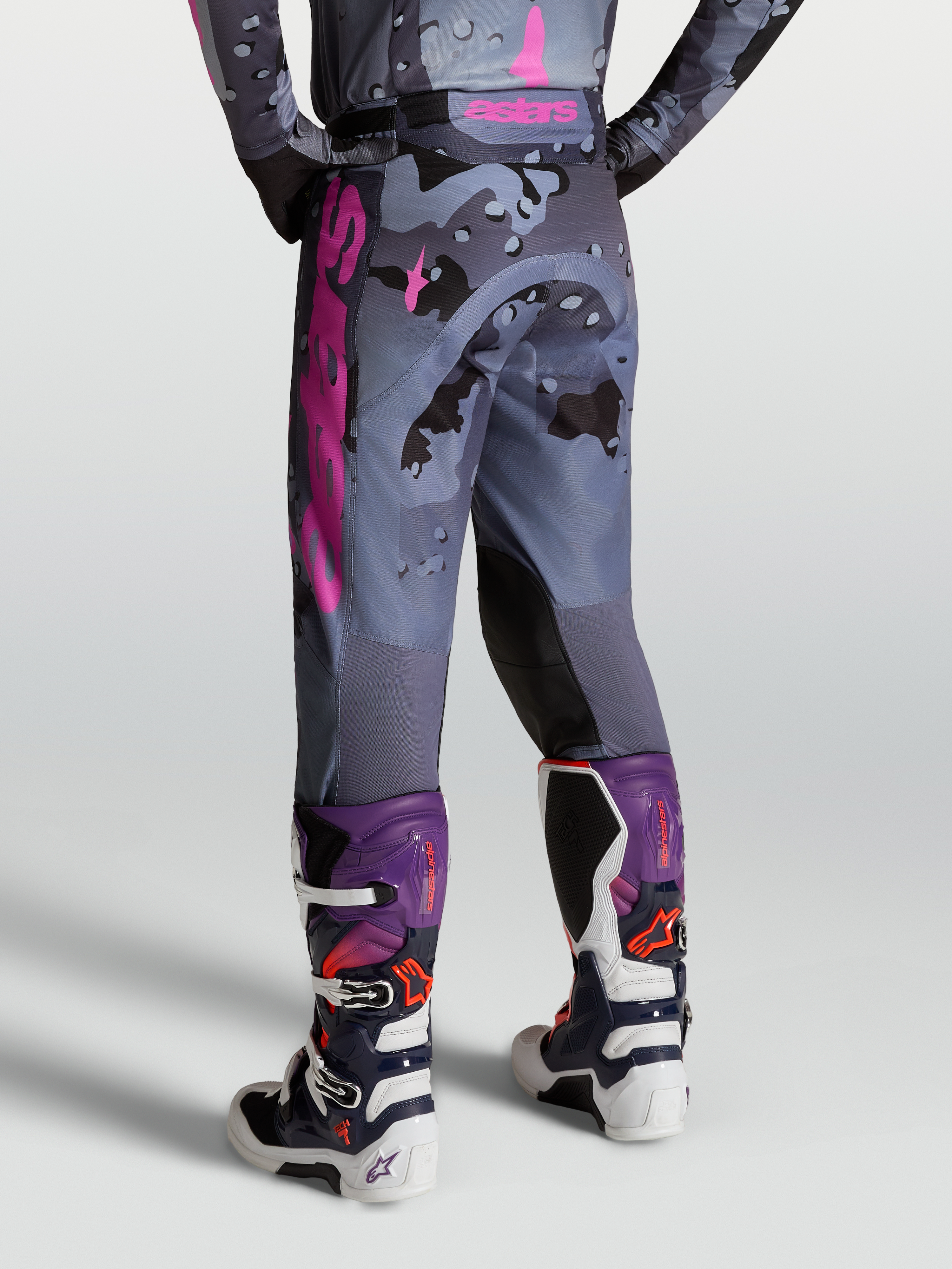 Alpinestars Pantalones Racer Lone, pantalones de motocross para hombre, diseño camuflaje gris y morado, vista trasera con botas Tech 7, equipo off-road