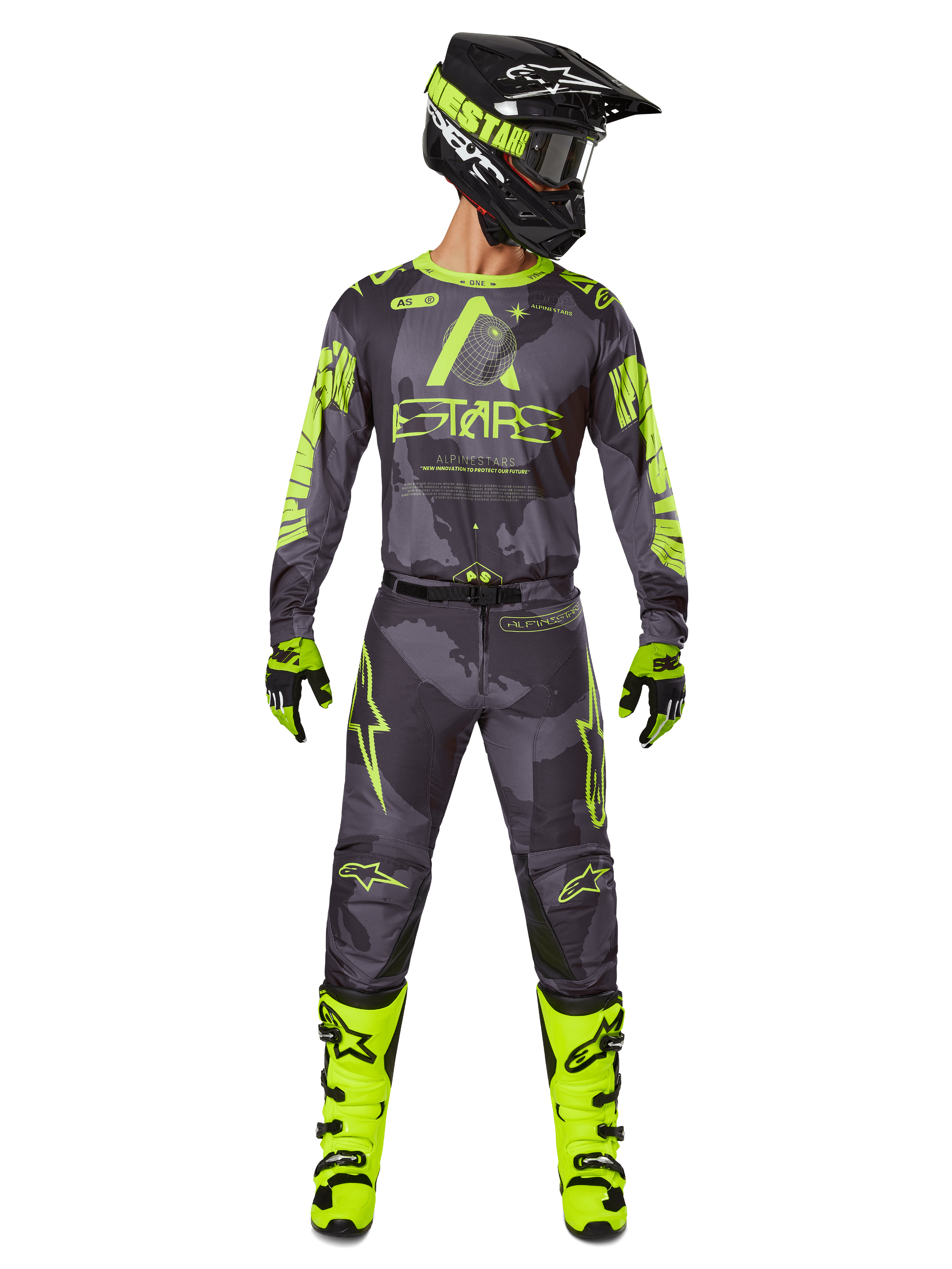 Piloto de motocross con equipamiento completo de carreras, jersey Alpinestars Racer Hollow 2025 y pantalones a juego en color Dark Camo Yellow Fluo, con gráficos llamativos en amarillo flúor sobre un fondo de camuflaje gris oscuro, combinado con guantes a juego, botas en amarillo flúor brillante y casco negro.
