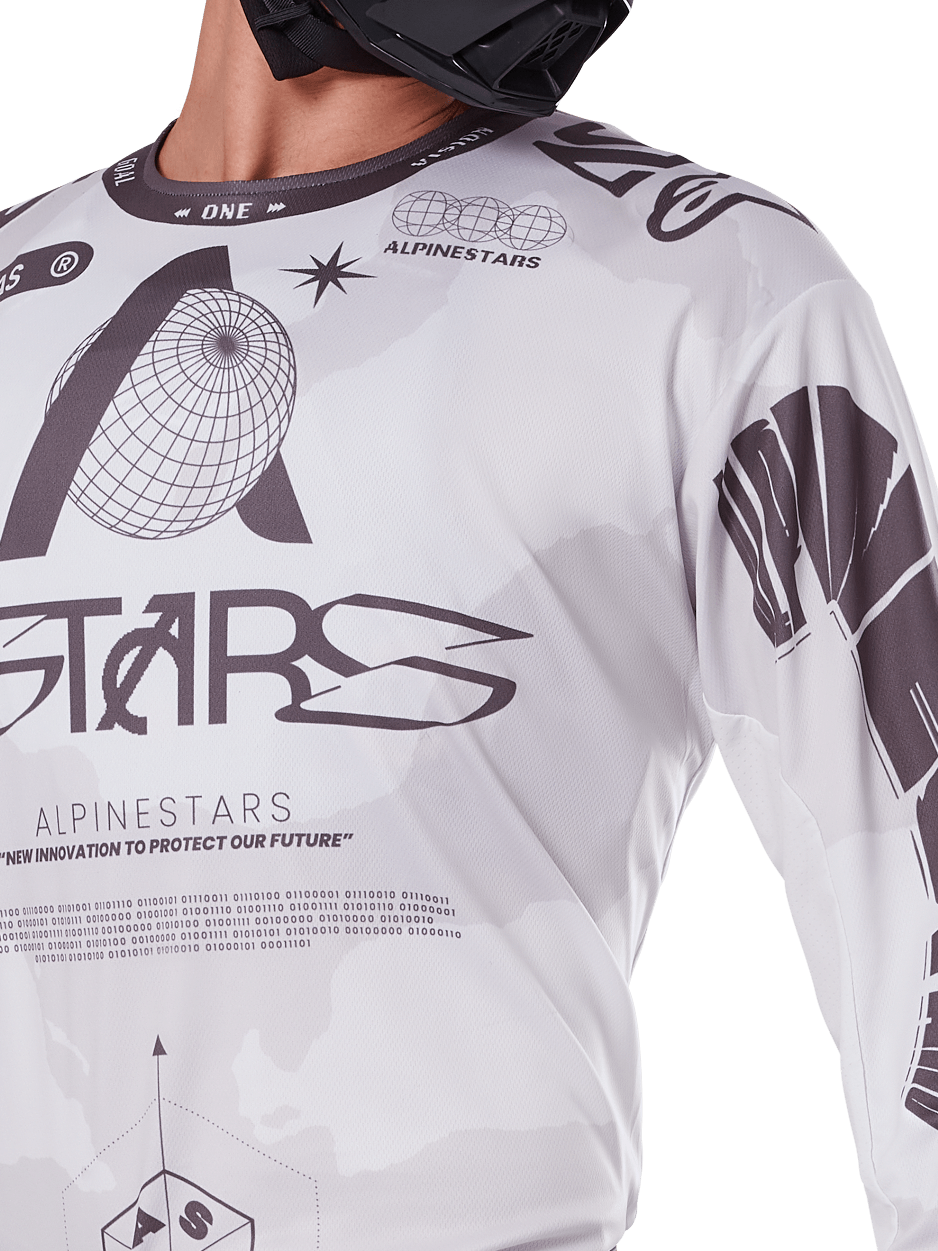 Primer plano del jersey Alpinestars Racer Hollow 2025, blanco y gris, con estampados gráficos negros con el logotipo del globo y código binario, ropa técnica de motocross para conducción off-road