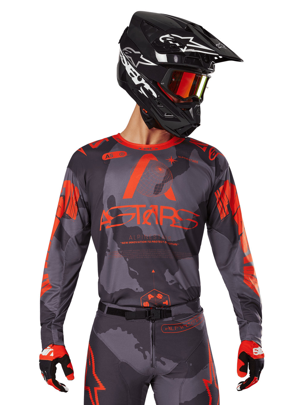 Alpinestars 2025 Racer Hollow Jersey, jersey de motocross, gris camuflaje y naranja flúor, combinado con un conjunto a juego de pantalones y guantes, con casco negro con gráficos blancos y gafas, logotipo ASTARS destacado, ropa deportiva protectora para todoterreno