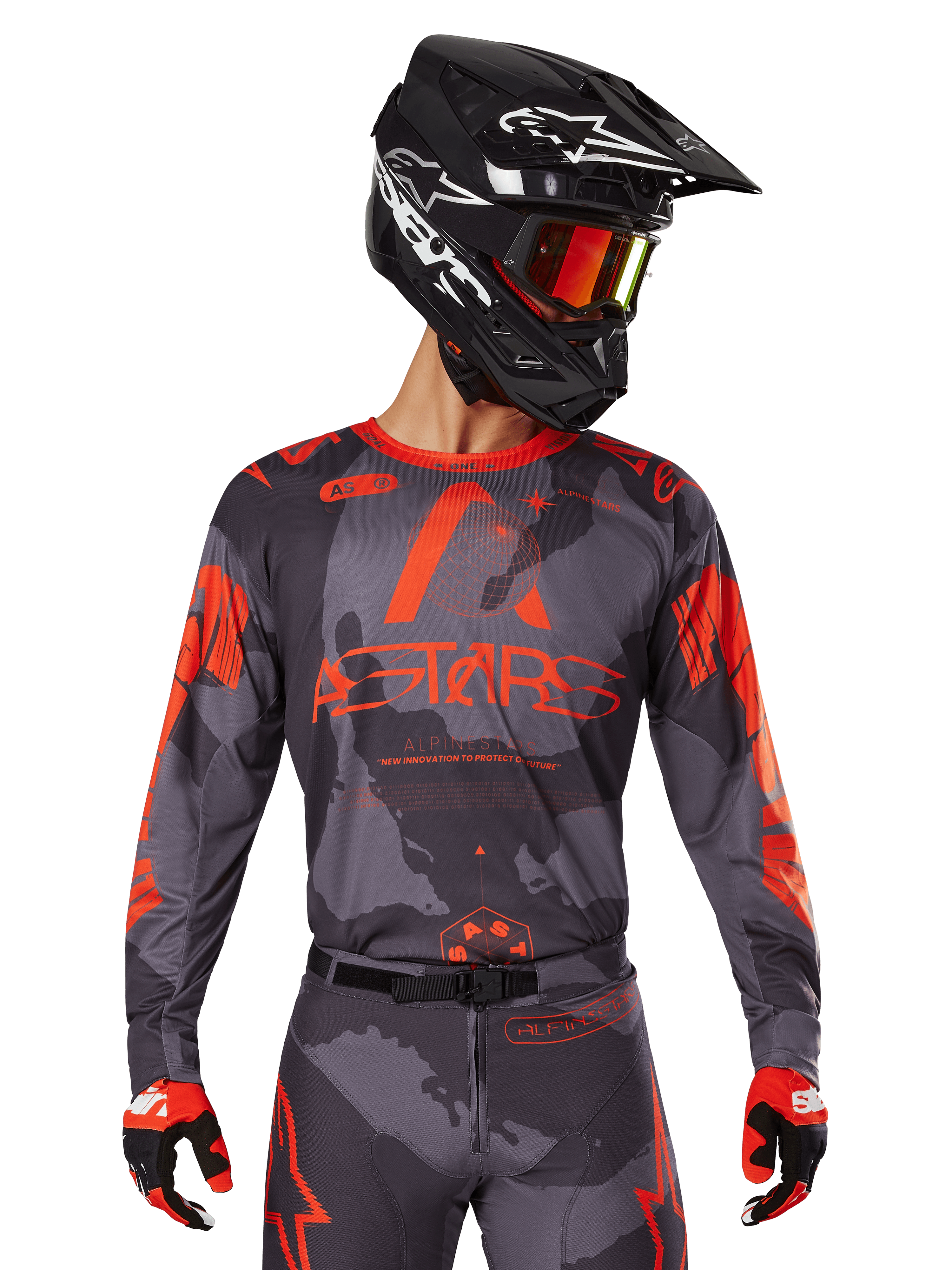 Alpinestars 2025 Racer Hollow Jersey, jersey de motocross, gris camuflaje y naranja flúor, combinado con un conjunto a juego de pantalones y guantes, con casco negro con gráficos blancos y gafas, logotipo ASTARS destacado, ropa deportiva protectora para todoterreno
