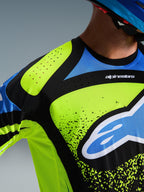 Alpinestars 2026 Techstar Nomur Jersey, close-up of the chest and shoulder in Dark Navy, Yellow Fluo, and Blue, featuring laser-cut ventilation perforations, seamless bonded collar, and bold Alpinestars branding, performance motocross gear.