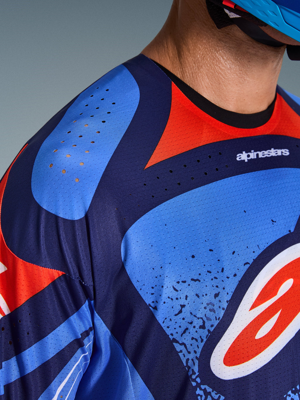 Alpinestars 2026 Techstar Nomur Jersey, close-up of chest and shoulder area, navy blue and red design with laser-cut ventilation holes, technical poly-fabric for motocross performance