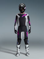 Piloto de motocross con equipamiento completo de competición, jersey Alpinestars 2026 Fluid Grid y pantalones a juego en negro y gris claro con detalles en púrpura vibrante, casco negro con gafas púrpuras, botas de motocross blancas y guantes negros, conjunto coordinado para rendimiento off-road