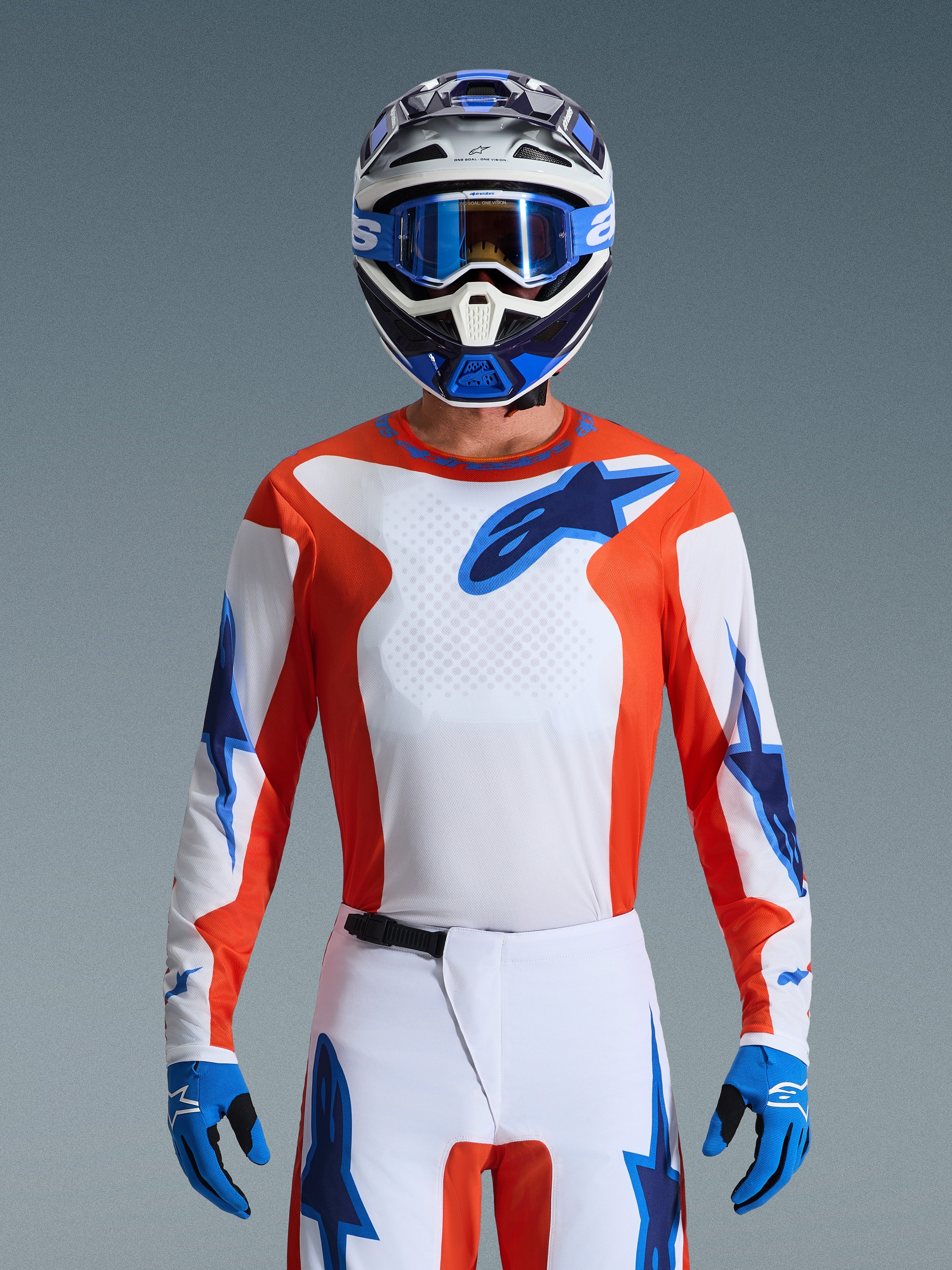 Alpinestars 2026 Fluid Grid Gear Set, Motocross rider wearing orange and white jersey with blue star logos, white pants with blue accents, matching blue and white helmet with blue goggles and gloves, complete off-road racing outfit