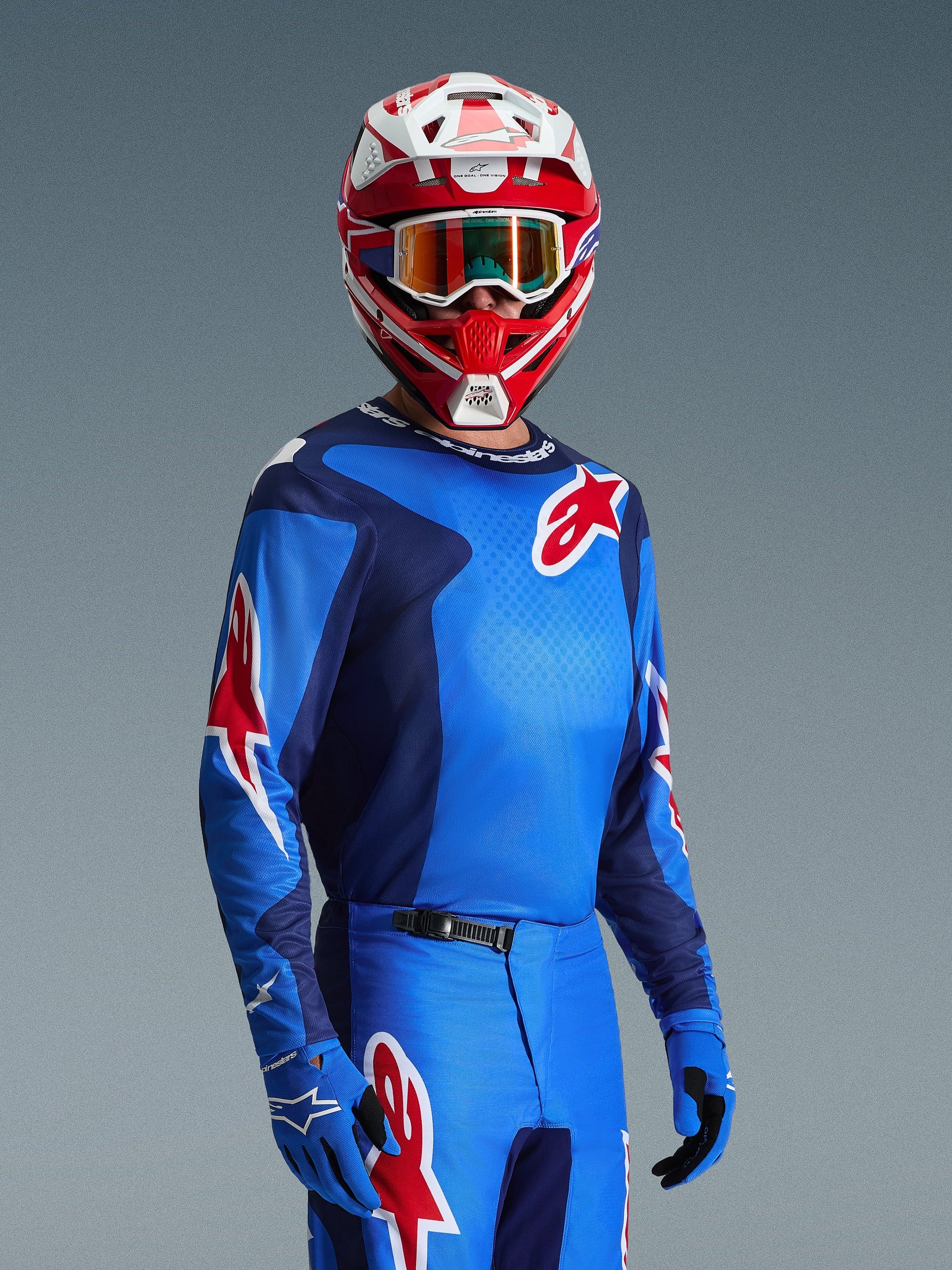 Alpinestars Fluid Grid Jersey 2026, jersey de motocross en azul y rojo con logotipos rojos de la estrella Alpinestars, combinado con pantalones azules a juego, guantes azules y casco rojo y blanco con gafas