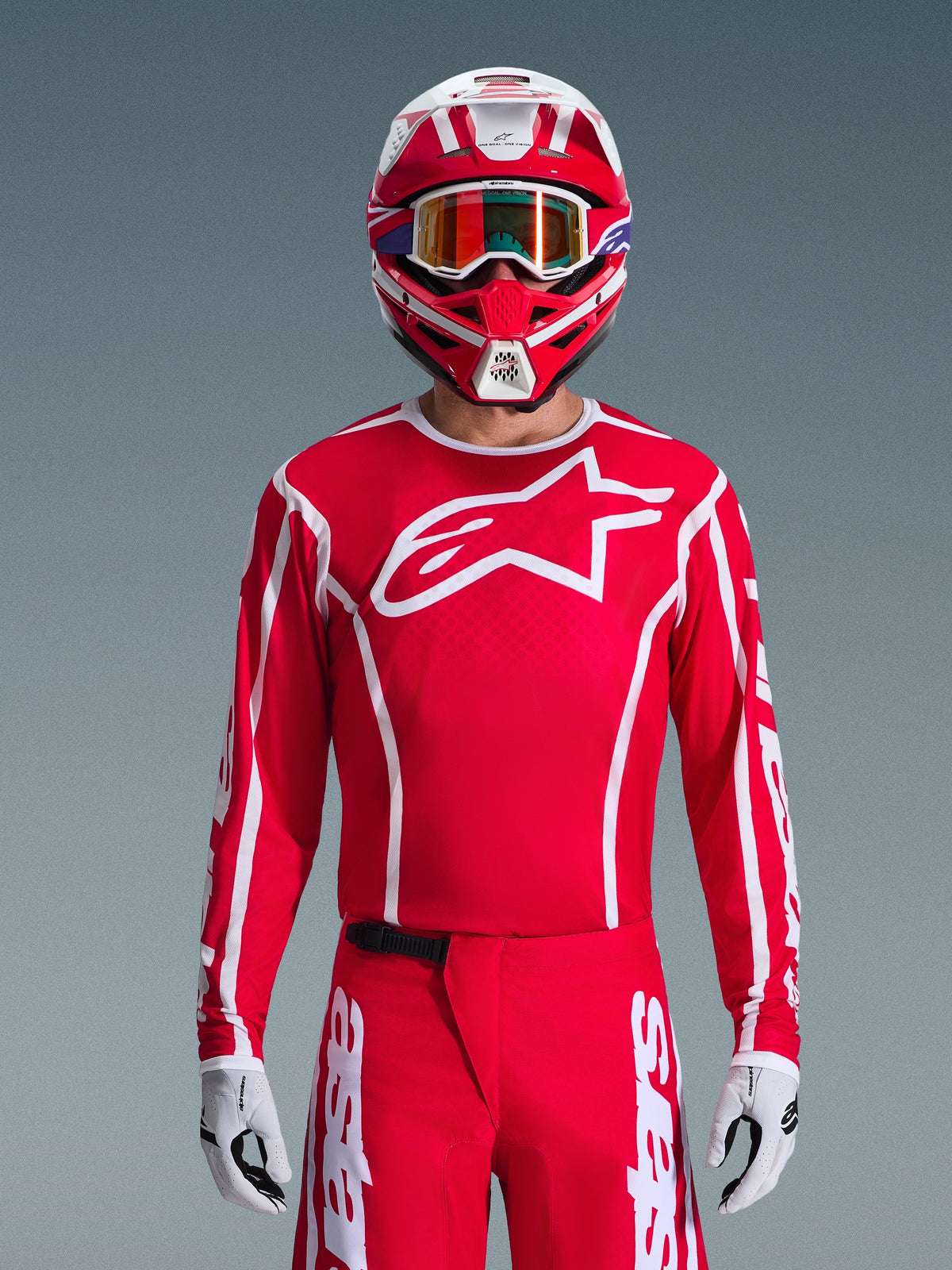 Alpinestars 2026 Fluid Apex Jersey, jersey de motocross, rojo y blanco, usado por un piloto con un casco rojo y blanco a juego y gafas naranjas, con un logotipo blanco prominente en el pecho, ajuste atlético, parte de un conjunto coordinado de equipamiento para carreras todoterreno