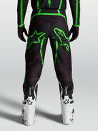 Alpinestars Pantalones Fluid Apex V2, pantalones de motocross para hombre, negros y verde flúor con gráficos de estrella, vista trasera en modelo.