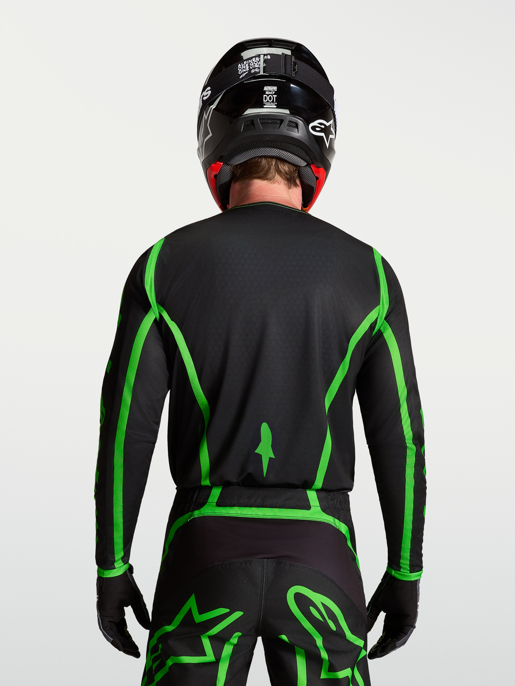 Alpinestars Jersey Fluid Apex V2, jersey de motocross, negro y verde fluorescente, vista trasera en modelo con cobertura trasera extendida para conducción off-road, diseño ligero y transpirable