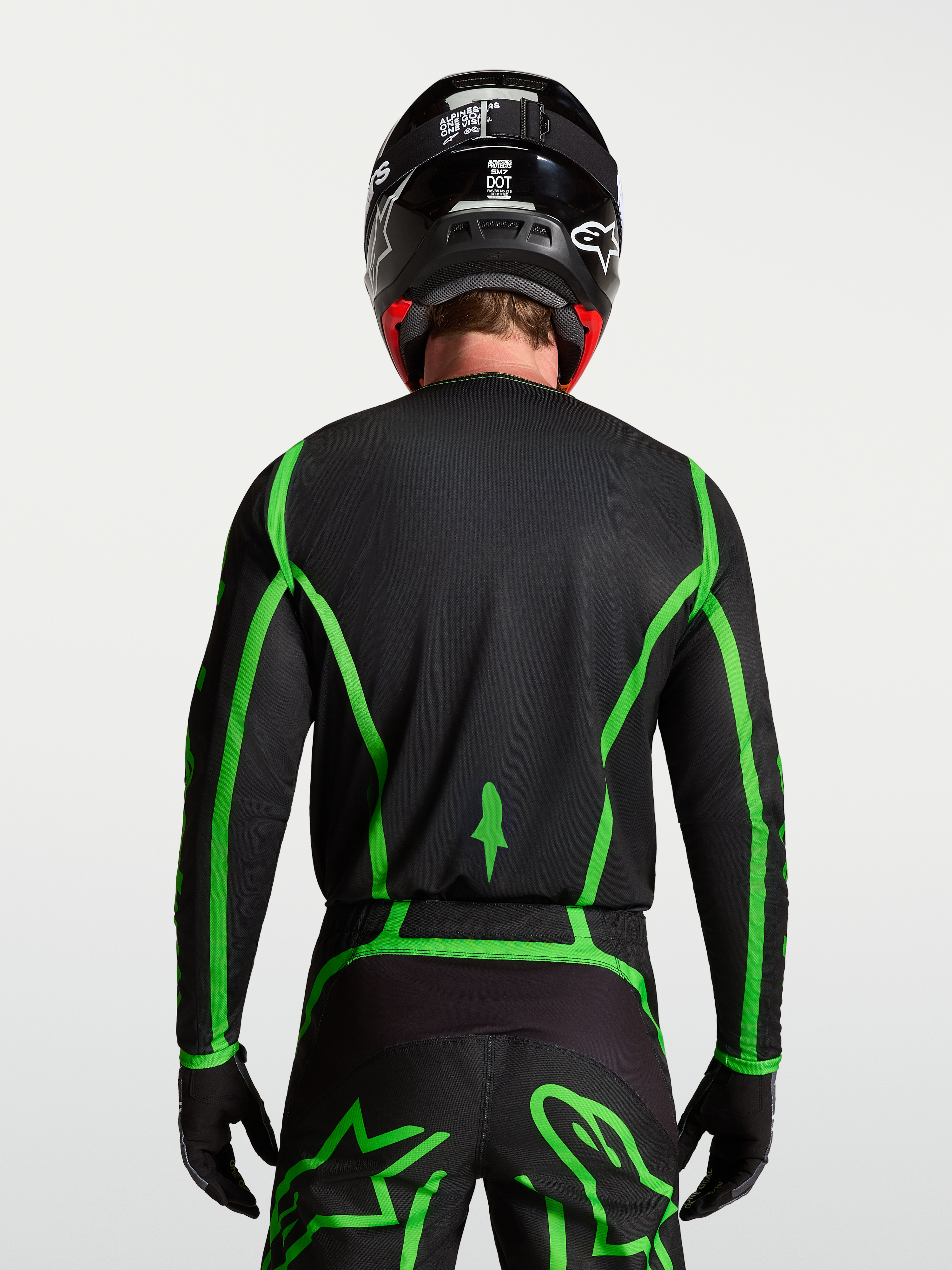 Alpinestars Jersey Fluid Apex V2, jersey de motocross, negro y verde fluorescente, vista trasera en modelo con cobertura trasera extendida para conducción off-road, diseño ligero y transpirable