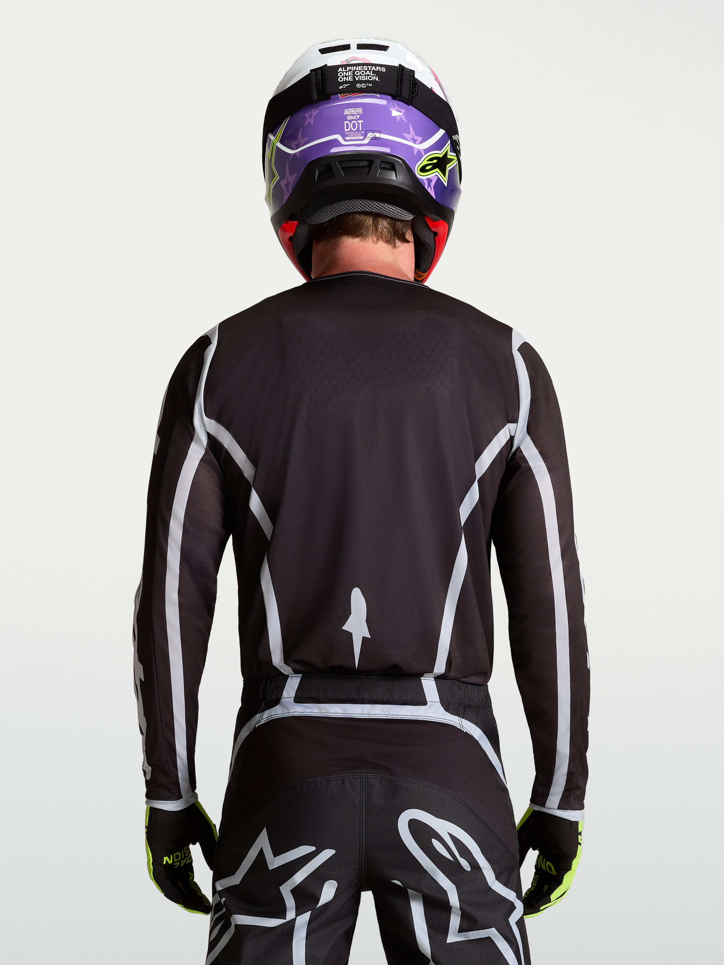 Jersey Fluid Apex V2 de Alpinestars, jersey de motocross para hombre, negro y plateado, vista trasera en modelo con ajuste atlético ergonómico.
