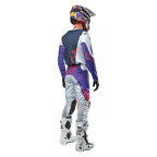 Piloto de motocross visto desde atrás con el jersey Alpinestars Racer Hoen 2024 en Gris Claro Naranja Intenso Negro, panel trasero azul marino con logo de estrella naranja, mangas moradas, combinado con pantalones de carreras a juego y botas blancas