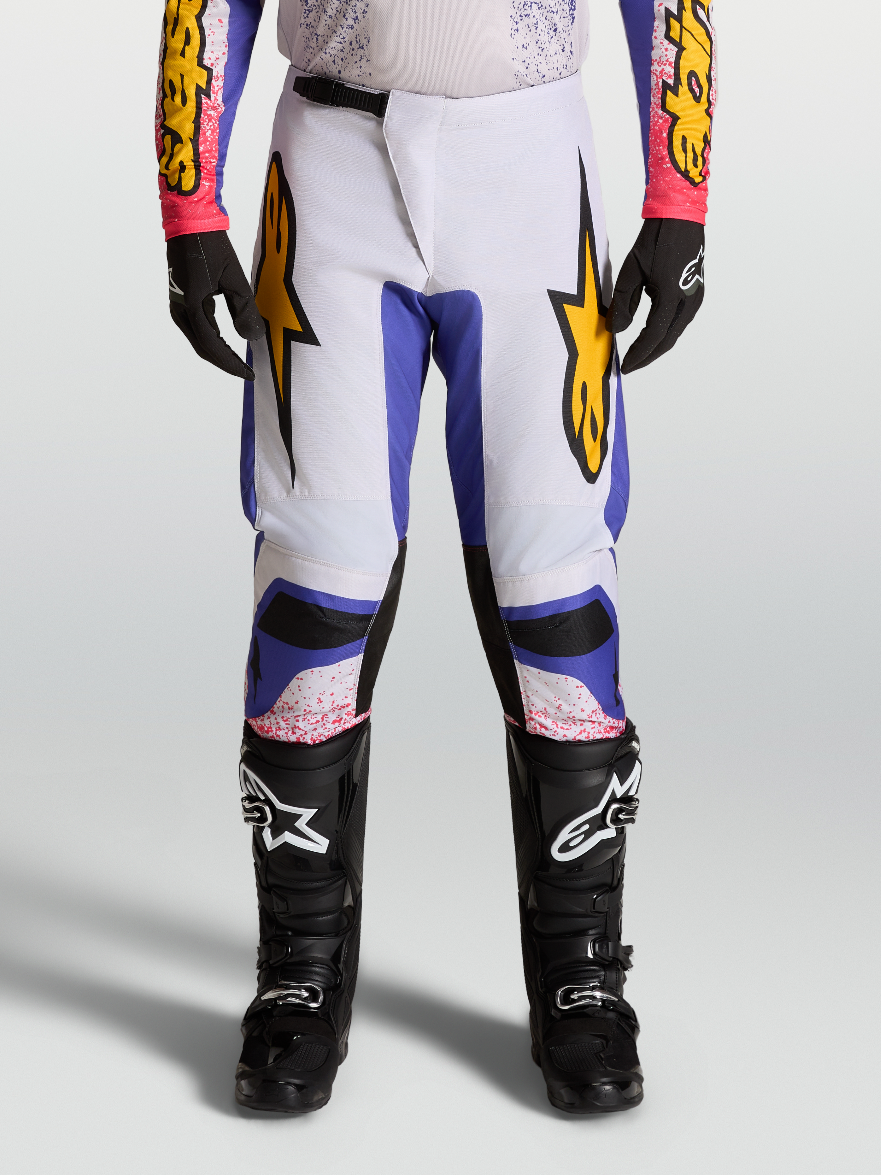 Alpinestars Pantalones Fluid Drag 2027, pantalones de motocross para hombre, lila claro y azul iris con detalles dorados.