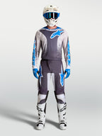 Jersey Alpinestars Fluid Drag de motocross para hombre, gris y azul, usado con casco y botas de carreras blancas