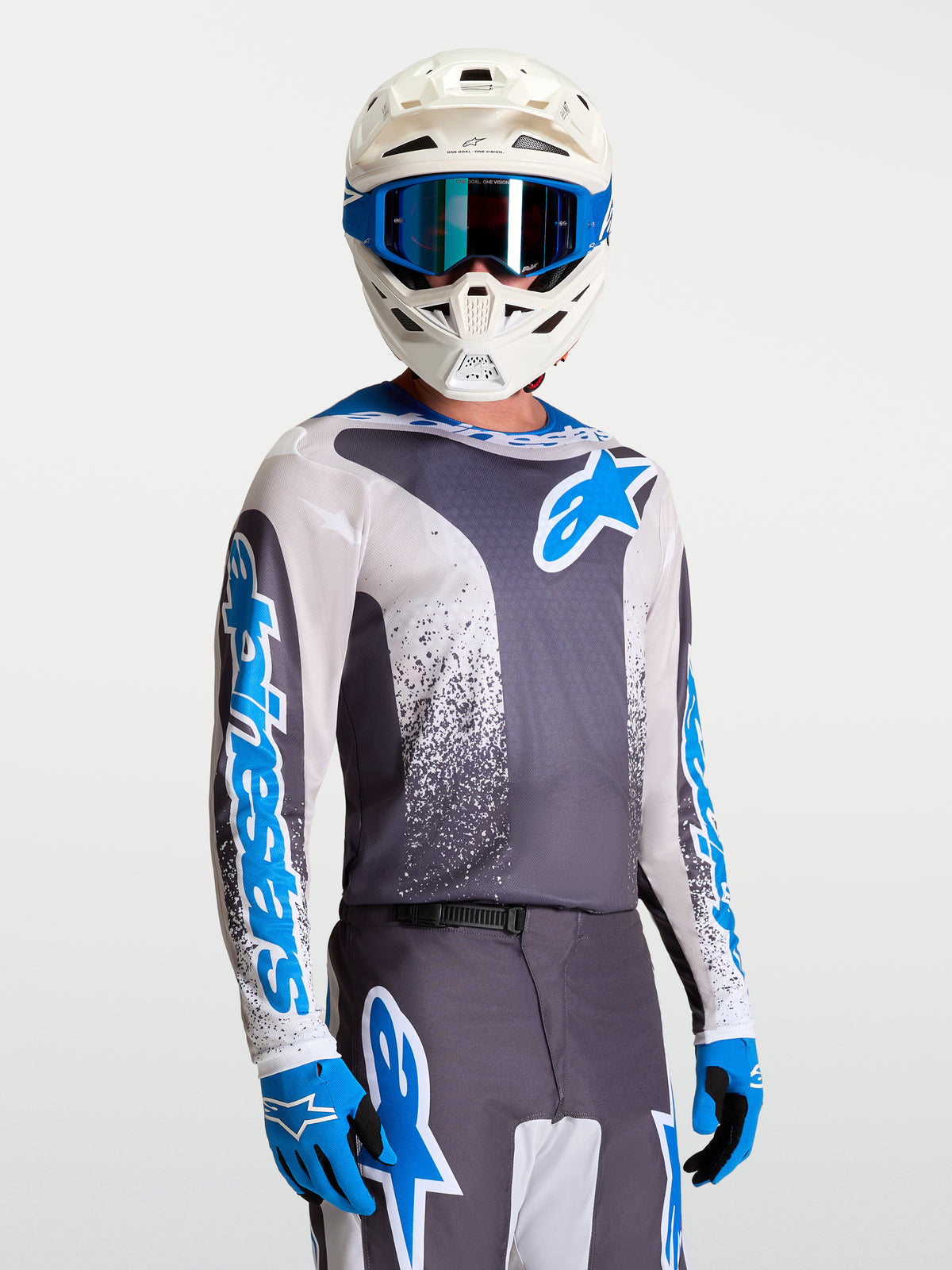 Alpinestars Jersey Fluid Drag, jersey de motocross para hombre, gris y azul, modelo con casco blanco y guantes coordinados