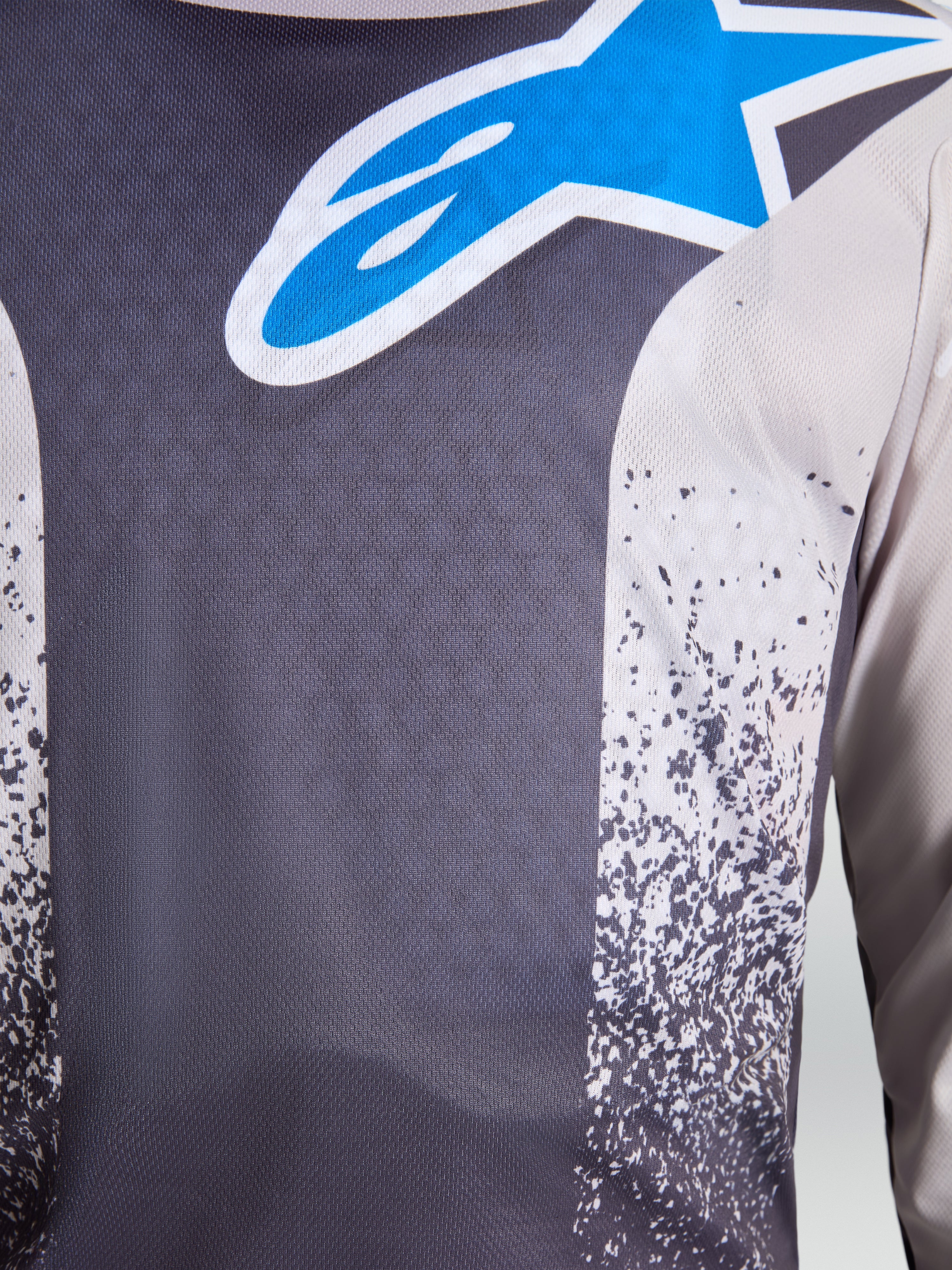 Jersey Fluid Drag de Alpinestars para hombre, gris y azul, primer plano de tejido transpirable con el logotipo de estrella.
