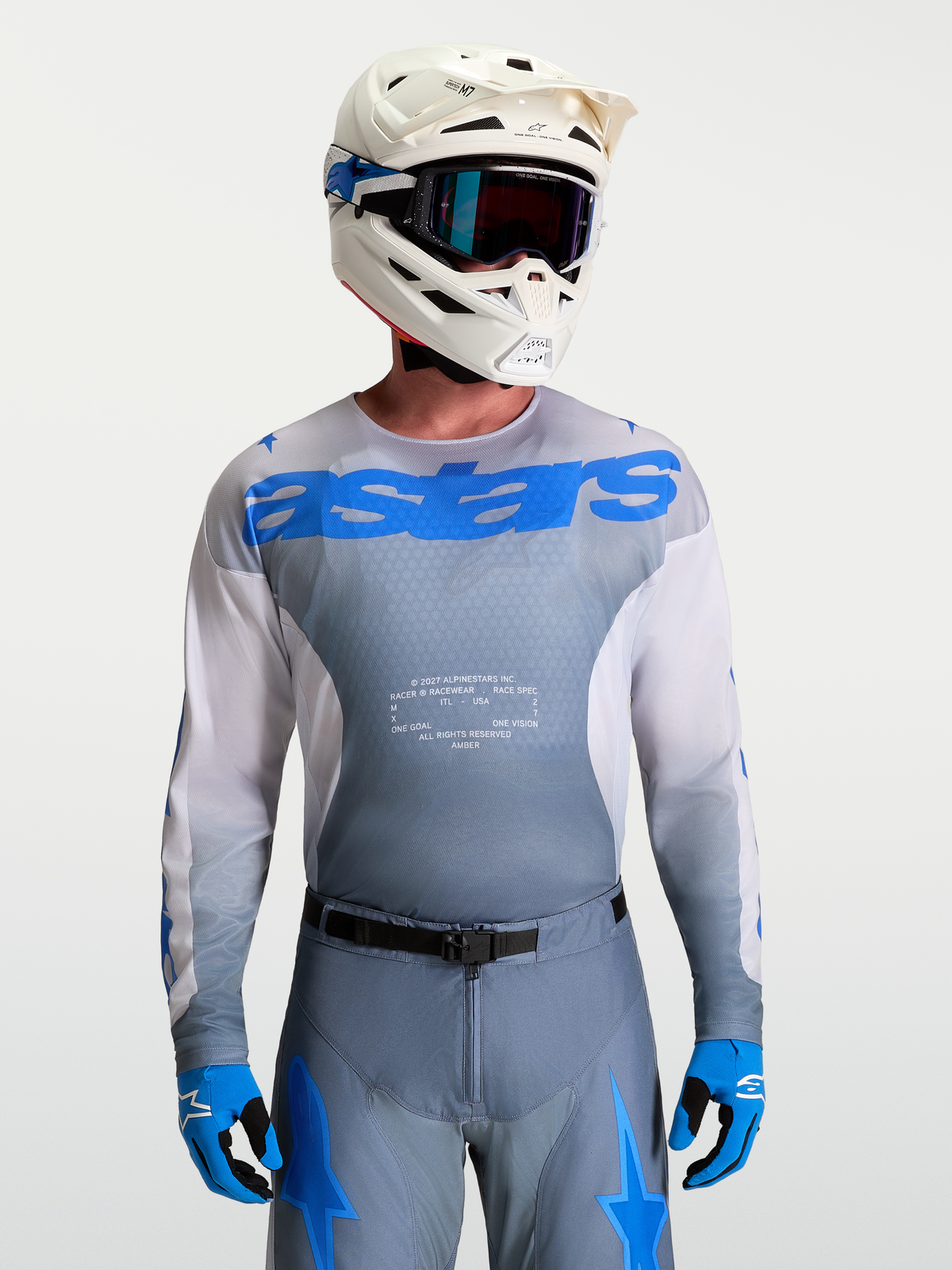 Alpinestars Jersey Racer Amber, equipo de motocross para hombre en gris y azul UCLA, con casco blanco y gafas de MX.
