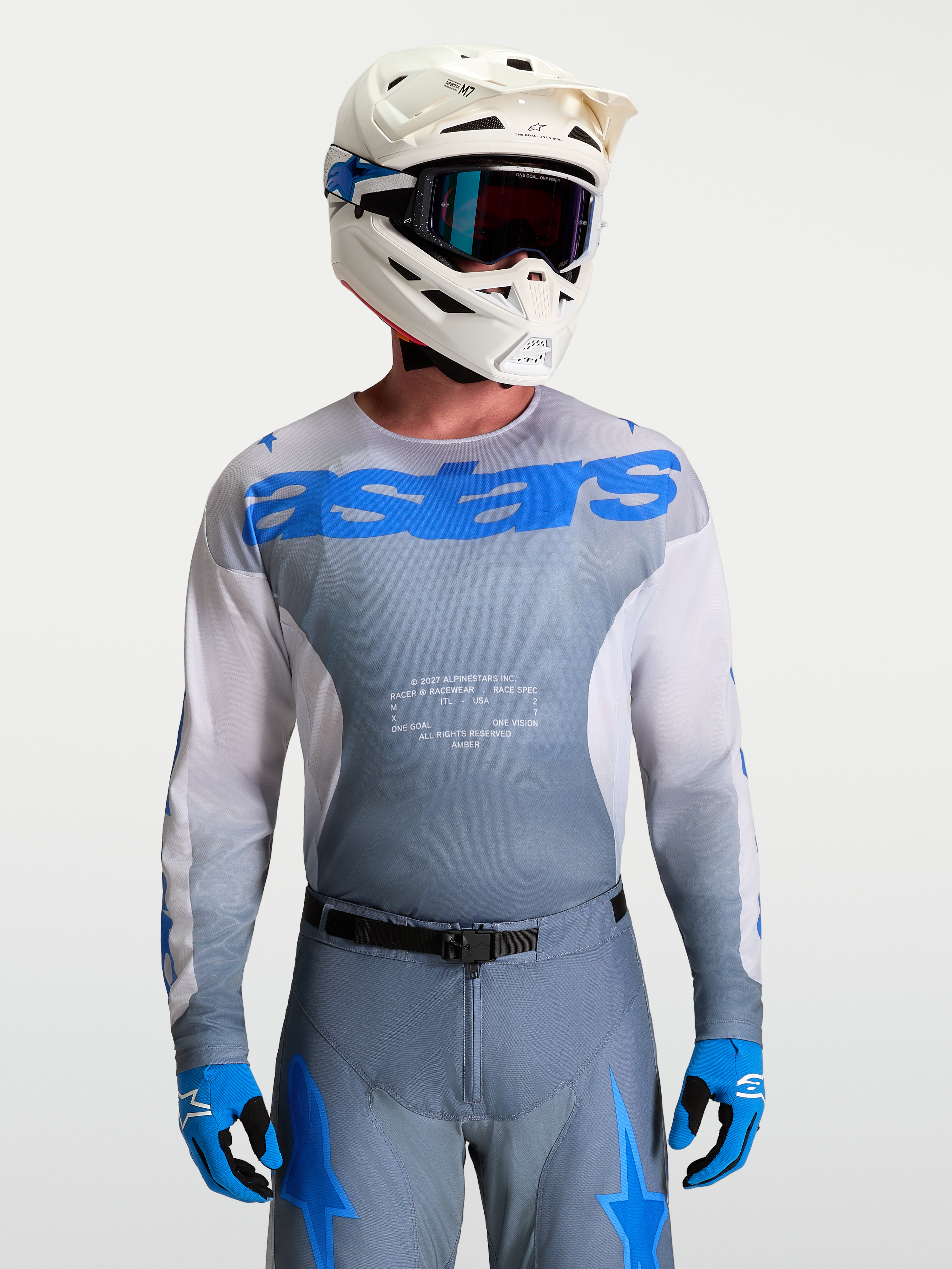 Alpinestars Jersey Racer Amber, equipo de motocross para hombre en gris y azul UCLA, con casco blanco y gafas de MX.