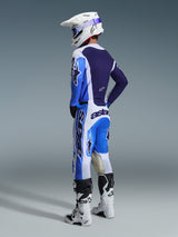 Motocross rider from a rear perspective wearing the Alpinestars 2026 Racer Air Portl Jersey in Ucla Blue and White, paired with matching motocross pants, white Supertech helmet, and white boots, showcasing a complete coordinated racing gear set.