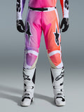 Alpinestars 2026 Racer Air Portl Pants, pantalones de motocross, degradado vibrante en púrpura, rosa y naranja, con logotipos de estrellas llamativos en los muslos, usados con botas de carreras blancas y guantes negros, diseñados para el pilotaje off-road de alto rendimiento