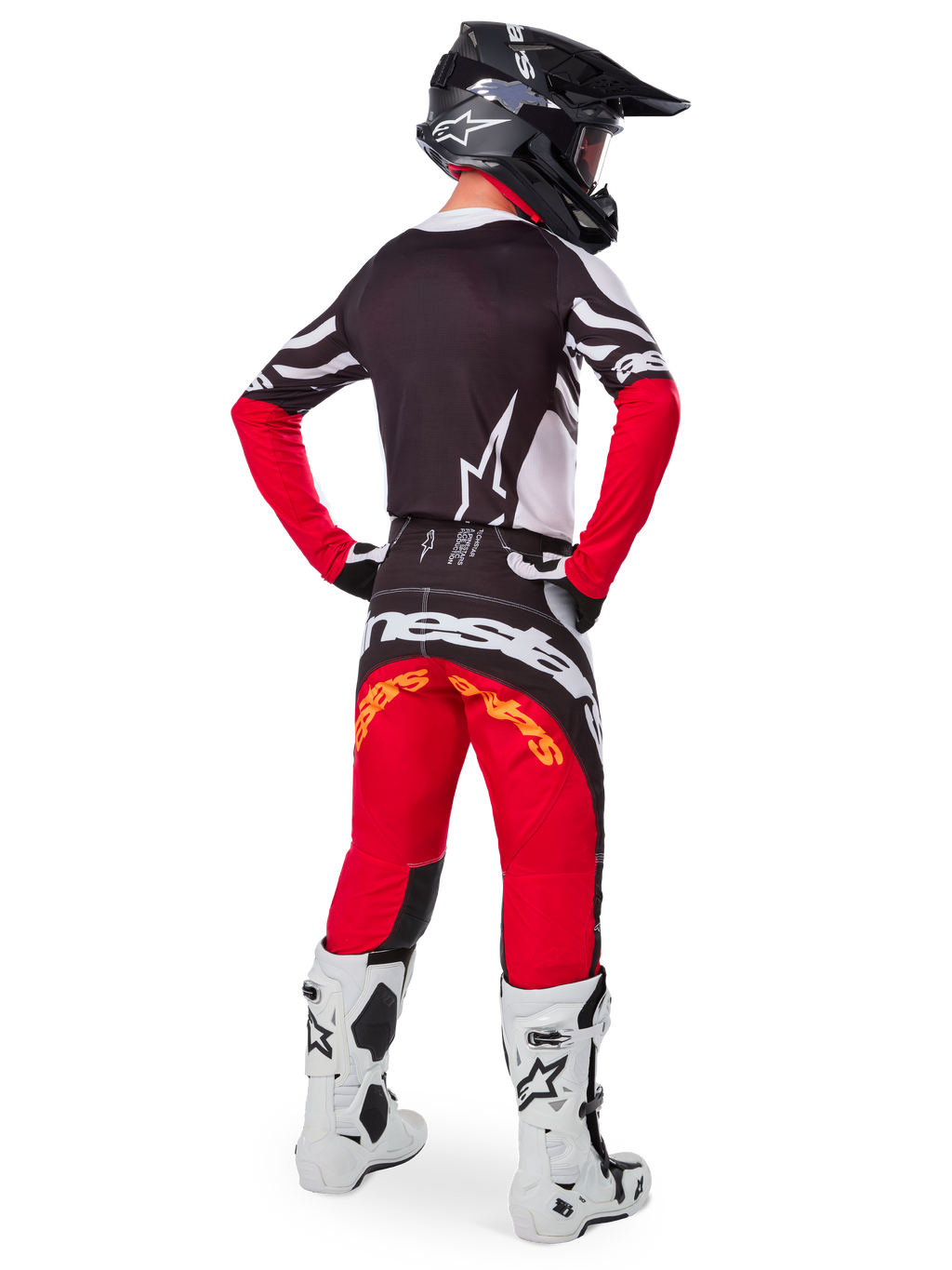 Piloto de motocross visto desde atrás con el jersey Alpinestars Techstar Deep Edición Limitada en negro, blanco y rojo intenso, que presenta una espalda negra con el logotipo de la estrella en blanco y mangas rojas, combinado con pantalones rojos y negros a juego, botas blancas y negras, y un casco negro para un equipamiento completo de carreras todoterreno.