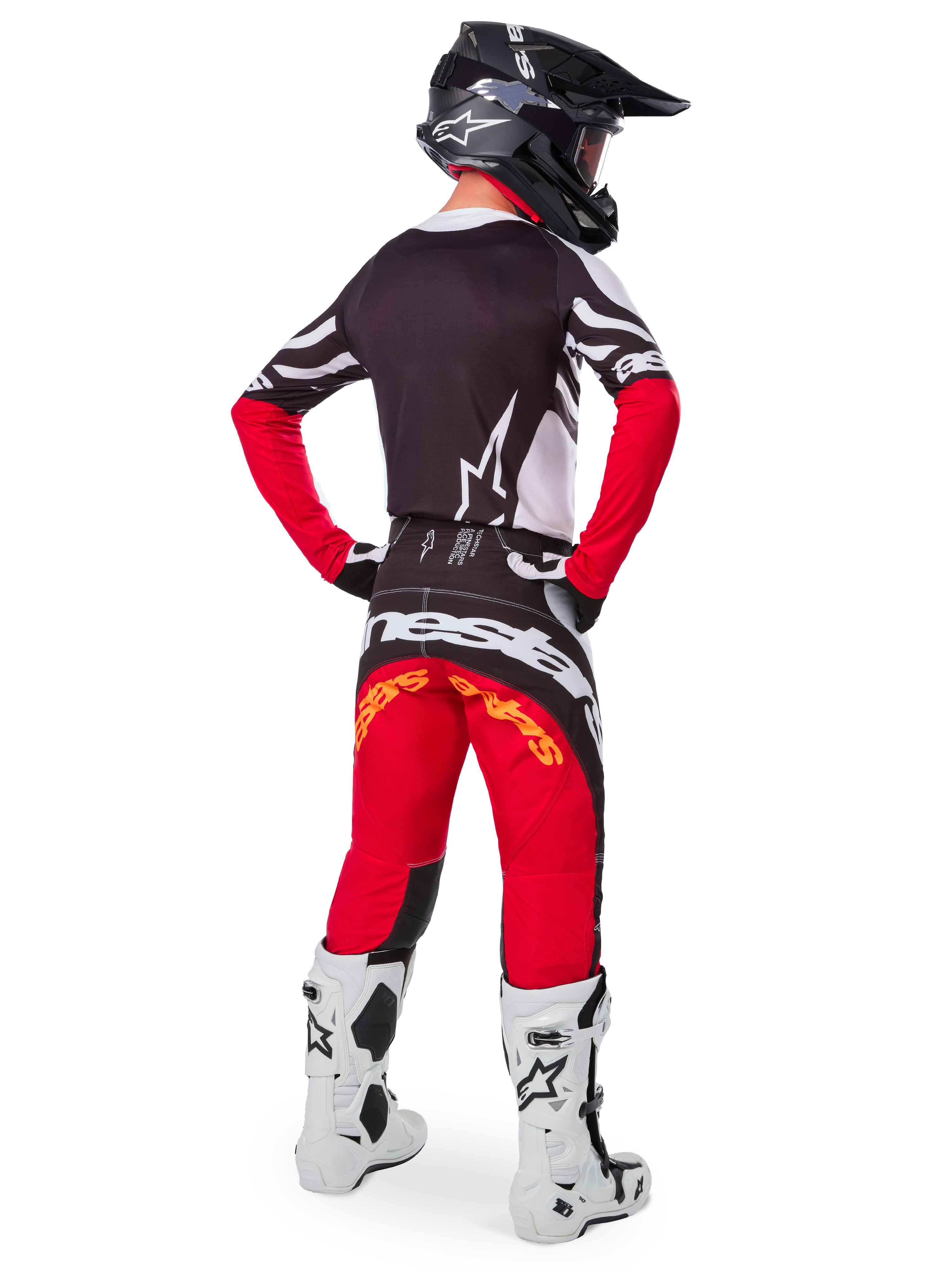 Piloto de motocross visto desde atrás con el jersey Alpinestars Techstar Deep Edición Limitada en negro, blanco y rojo intenso, que presenta una espalda negra con el logotipo de la estrella en blanco y mangas rojas, combinado con pantalones rojos y negros a juego, botas blancas y negras, y un casco negro para un equipamiento completo de carreras todoterreno.