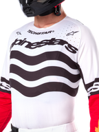 Alpinestars Limited Edition Techstar Deep Jersey, jersey de motocross blanco con rayas negras horizontales onduladas y mangas rojas, con logotipos de Alpinestars y Techstar, pequeñas perforaciones cortadas con láser en la parte superior del pecho para ventilación, equipamiento deportivo para off-road