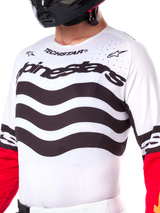 Alpinestars Limited Edition Techstar Deep Jersey, white motocross jersey with wavy black horizontal stripes and red sleeves, featuring Alpinestars and Techstar branding, small laser-cut perforations on the upper chest for ventilation, athletic off-road gear