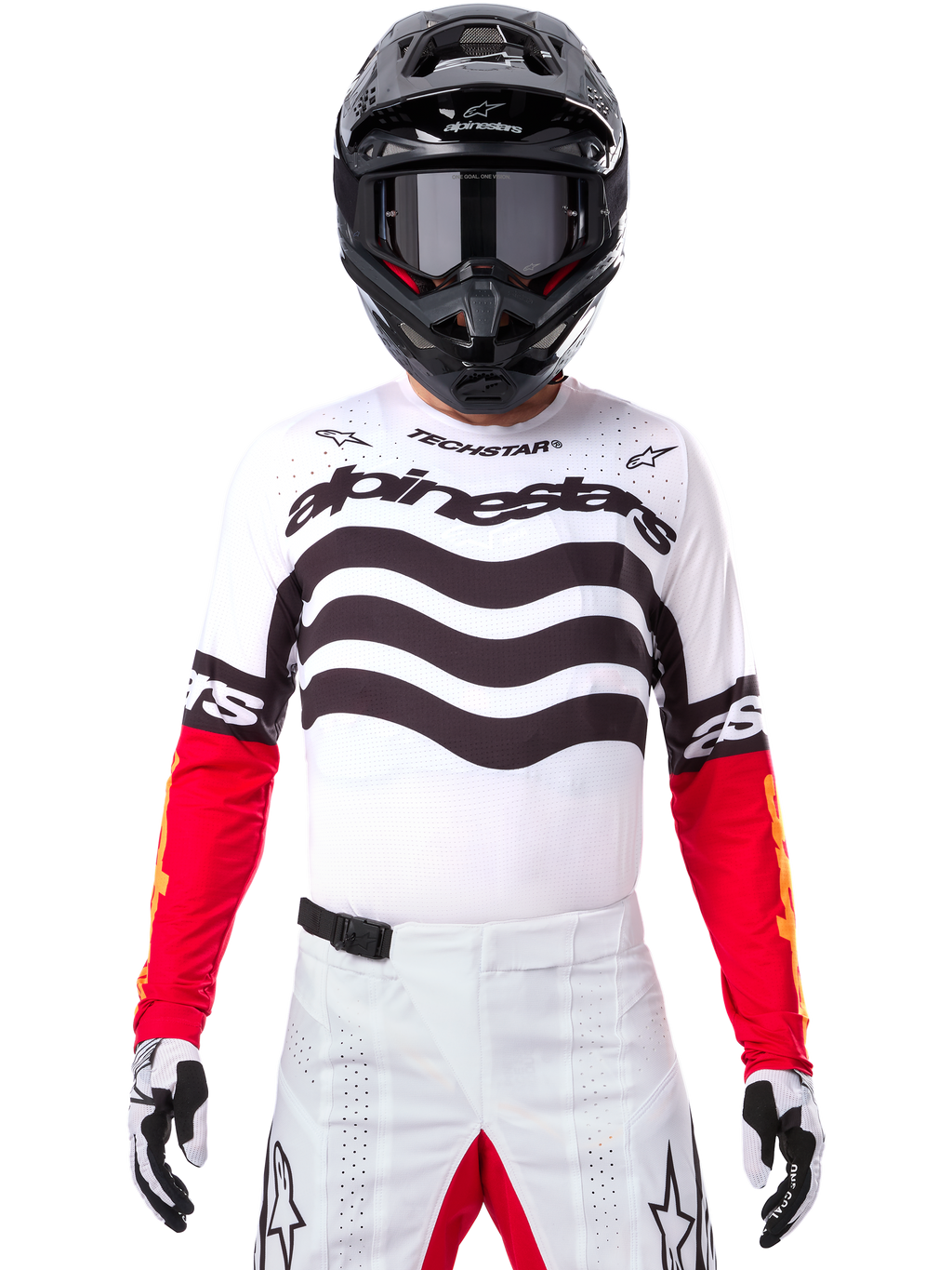 Piloto de motocross con equipamiento completo de competición, Jersey Techstar Deep Edición Limitada en blanco y negro con mangas rojas, con gráficos ondulados y el logotipo de Alpinestars destacado, pantalones de motocross blancos, casco y gafas negros, conjunto coordinado para carreras todoterreno