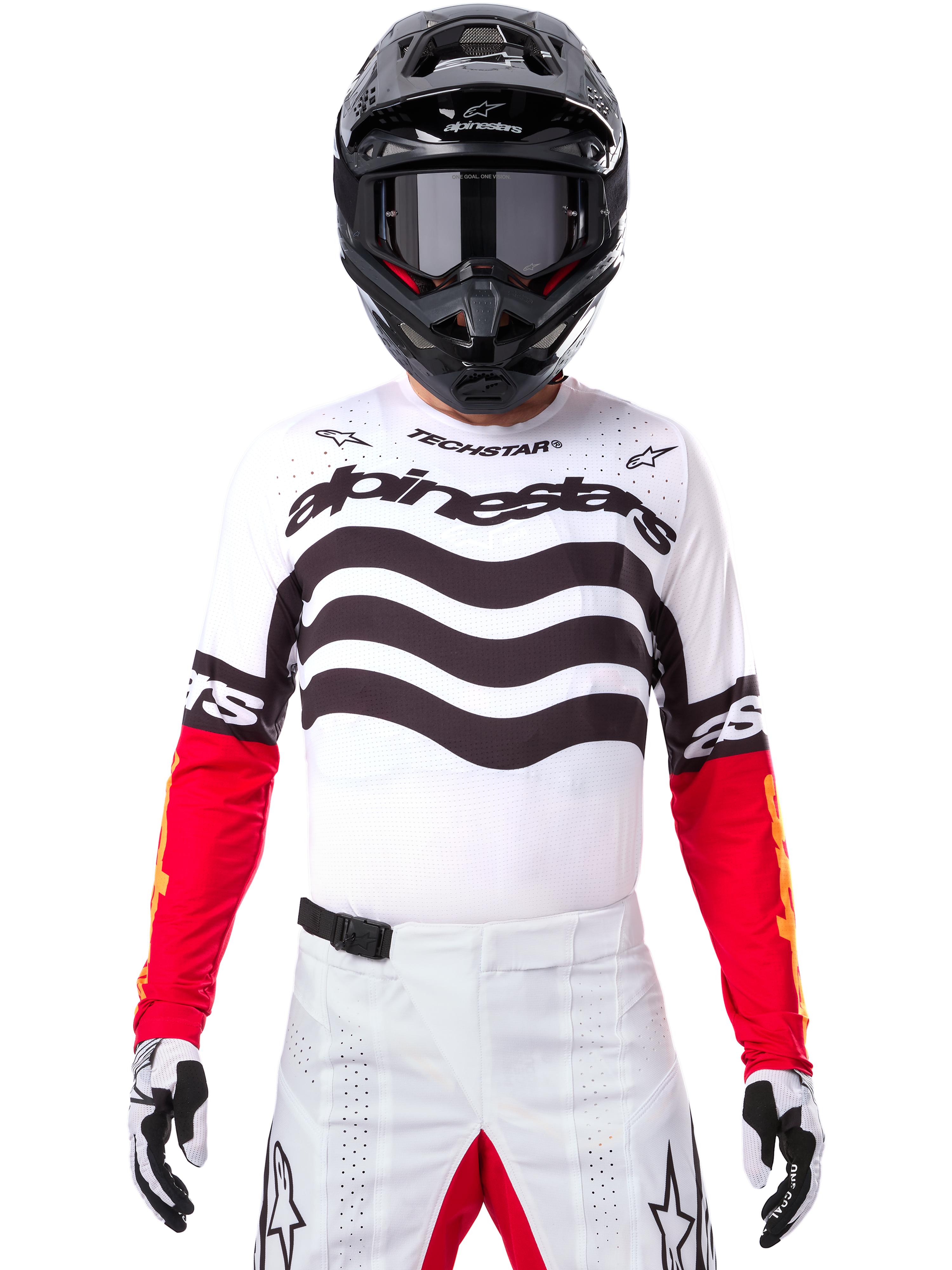Piloto de motocross con equipamiento completo de competición, Jersey Techstar Deep Edición Limitada en blanco y negro con mangas rojas, con gráficos ondulados y el logotipo de Alpinestars destacado, pantalones de motocross blancos, casco y gafas negros, conjunto coordinado para carreras todoterreno