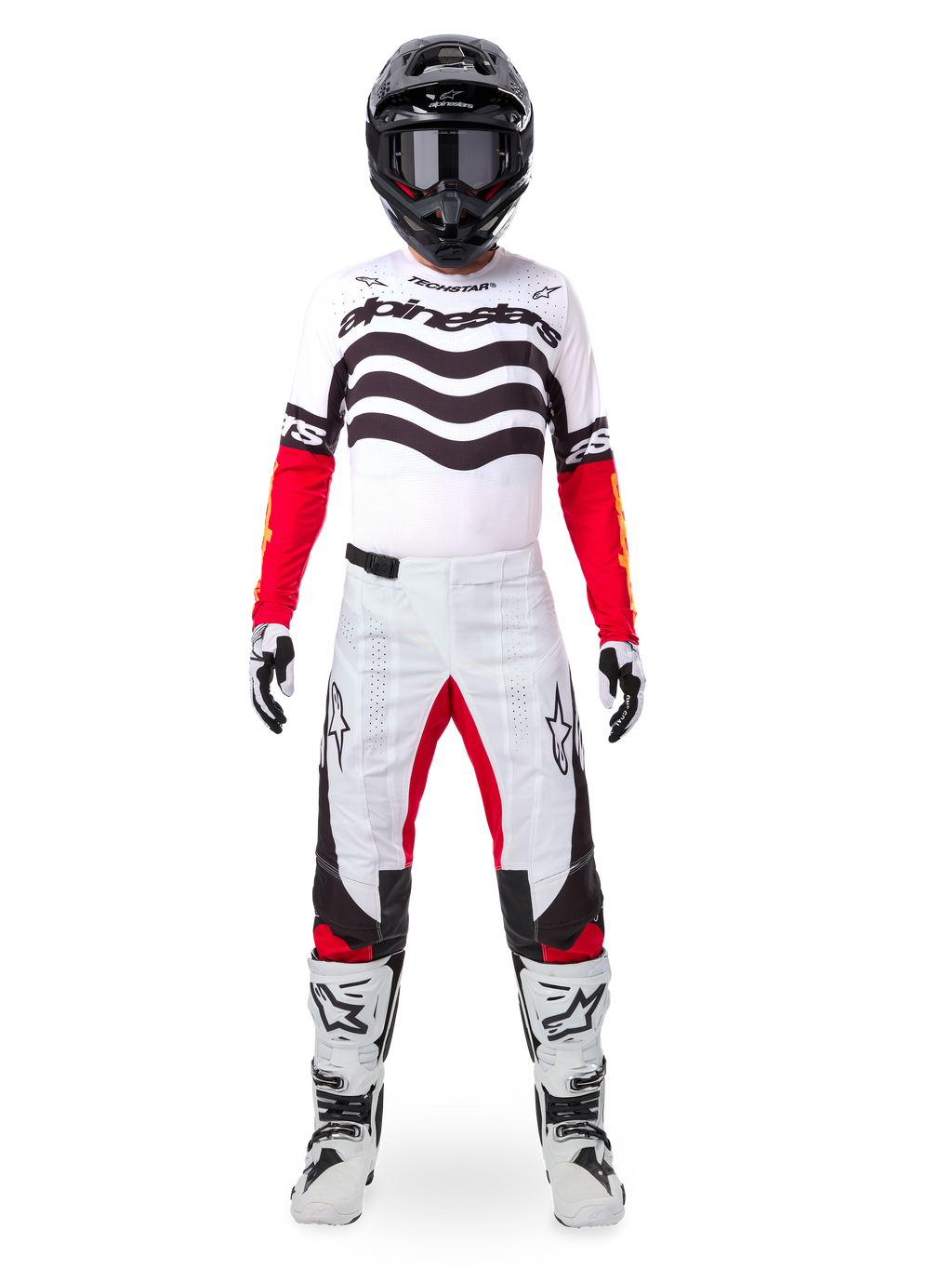 Piloto de motocross con el conjunto Alpinestars Techstar Deep Edición Limitada, jersey blanco con gráficos de ondas negras y mangas rojas, pantalones blancos y negros a juego con detalles rojos, casco negro con gafas oscuras y botas blancas, equipamiento profesional completo de competición todoterreno