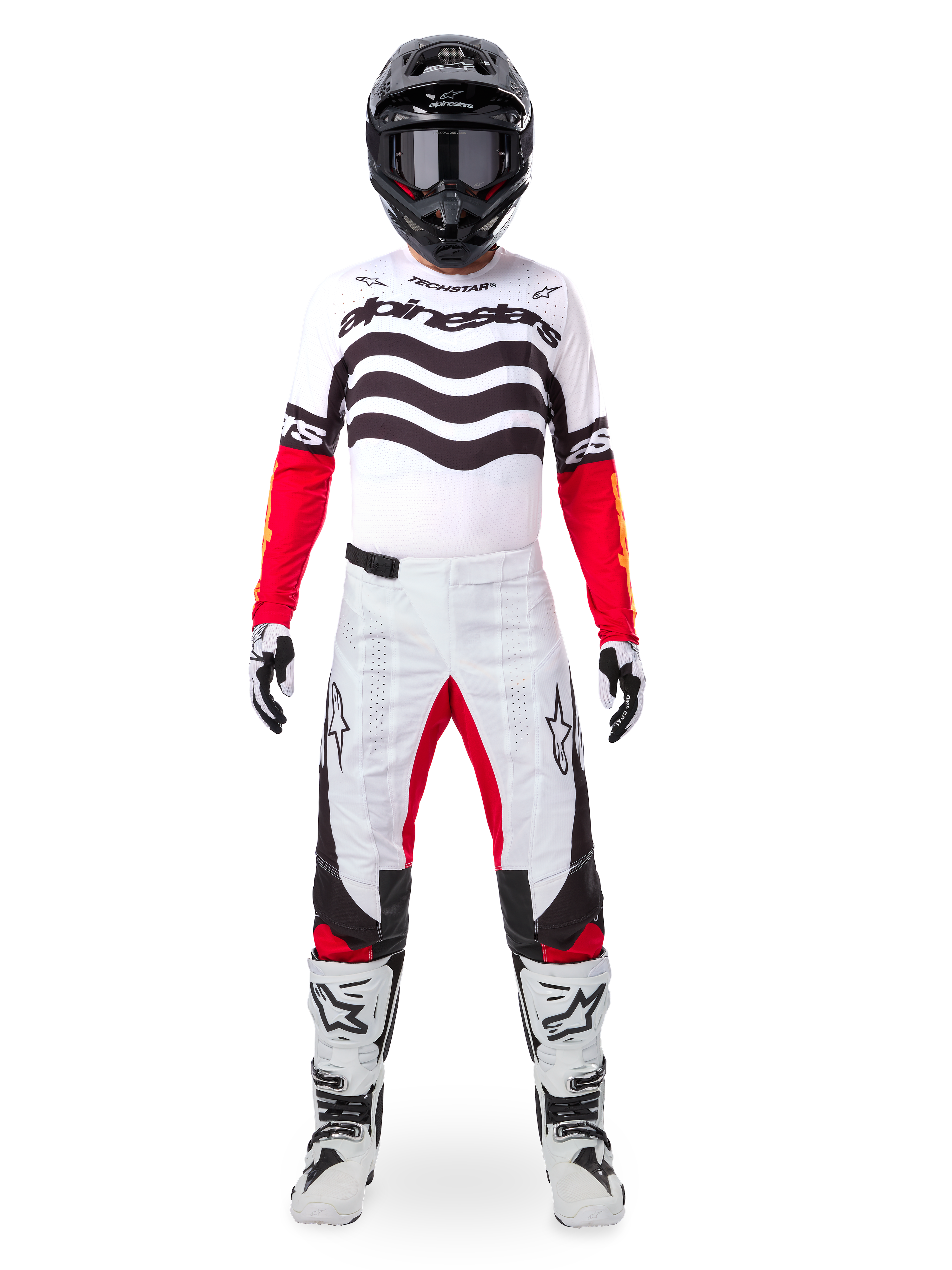 Piloto de motocross con el conjunto Alpinestars Techstar Deep Edición Limitada, jersey blanco con gráficos de ondas negras y mangas rojas, pantalones blancos y negros a juego con detalles rojos, casco negro con gafas oscuras y botas blancas, equipamiento profesional completo de competición todoterreno