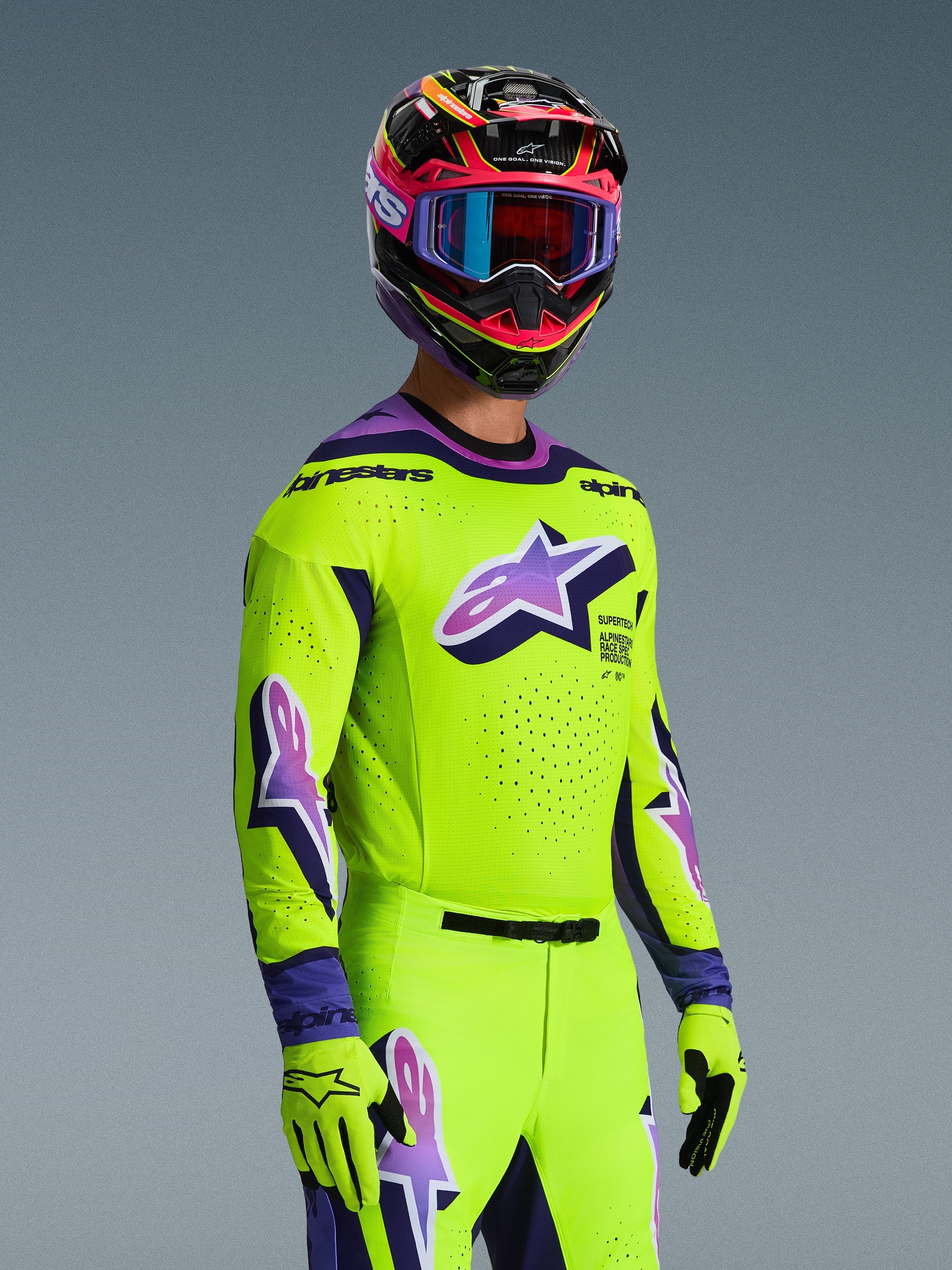 Motocross rider wearing the Alpinestars 2026 Supertech Vista Jersey, Bright Yellow with Purple and Black accents, matching yellow pants and gloves, multi-colored helmet with purple goggles, featuring laser-cut perforations and a large Astar logo on the chest, coordinated pro-level racing outfit