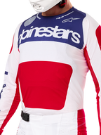 Alpinestars Techstar Fortitude Edición Limitada, conjunto de equipamiento de motocross en rojo, blanco y azul, con camiseta blanca, panel superior azul marino y gráfico central rojo, pantalones a juego con hebilla magnética SX2, ajuste atlético para carreras todoterreno