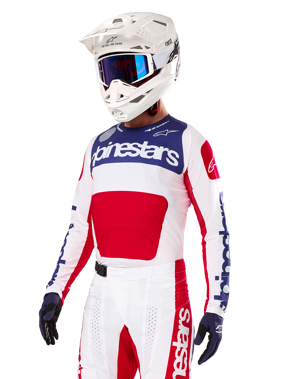 Piloto de motocross con el Jersey Alpinestars Techstar Fortitude Edición Limitada, en rojo brillante, blanco y azul, con casco blanco, gafas azules y pantalones a juego, equipación de competición de alto rendimiento para off-road