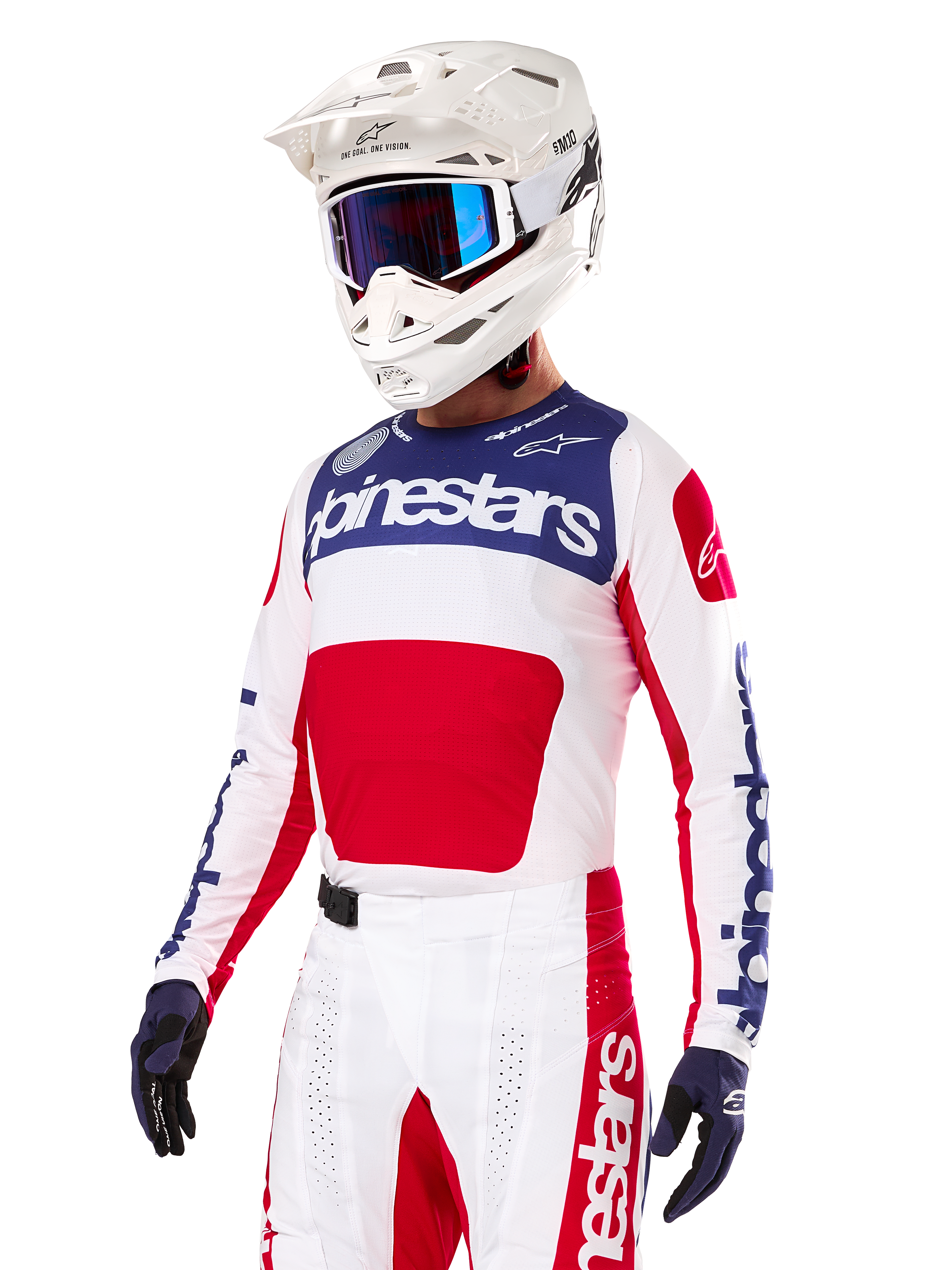 Piloto de motocross con el Jersey Alpinestars Techstar Fortitude Edición Limitada, en rojo brillante, blanco y azul, con casco blanco, gafas azules y pantalones a juego, equipación de competición de alto rendimiento para off-road