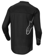 Alpinestars Fluid Graphite Jersey, camiseta de motocross, negro y gris oscuro, vista trasera, con un gran logotipo de Alpinestars en gris en el lateral y gráficos en las mangas, tejido ligero que absorbe la humedad para carreras todoterreno