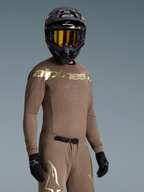 Alpinestars Supertech Air Gold edición limitada, conjunto de motocross marrón y dorado con ventilación láser, mostrado en piloto.
