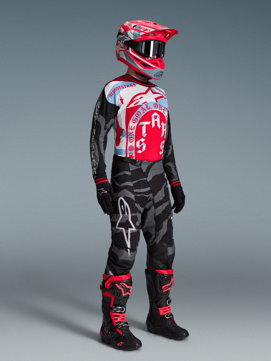 Conjunto Alpinestars Techstar Beast Coast, jersey gráfico rojo y azul, pantalones de camuflaje y botas de motocross.