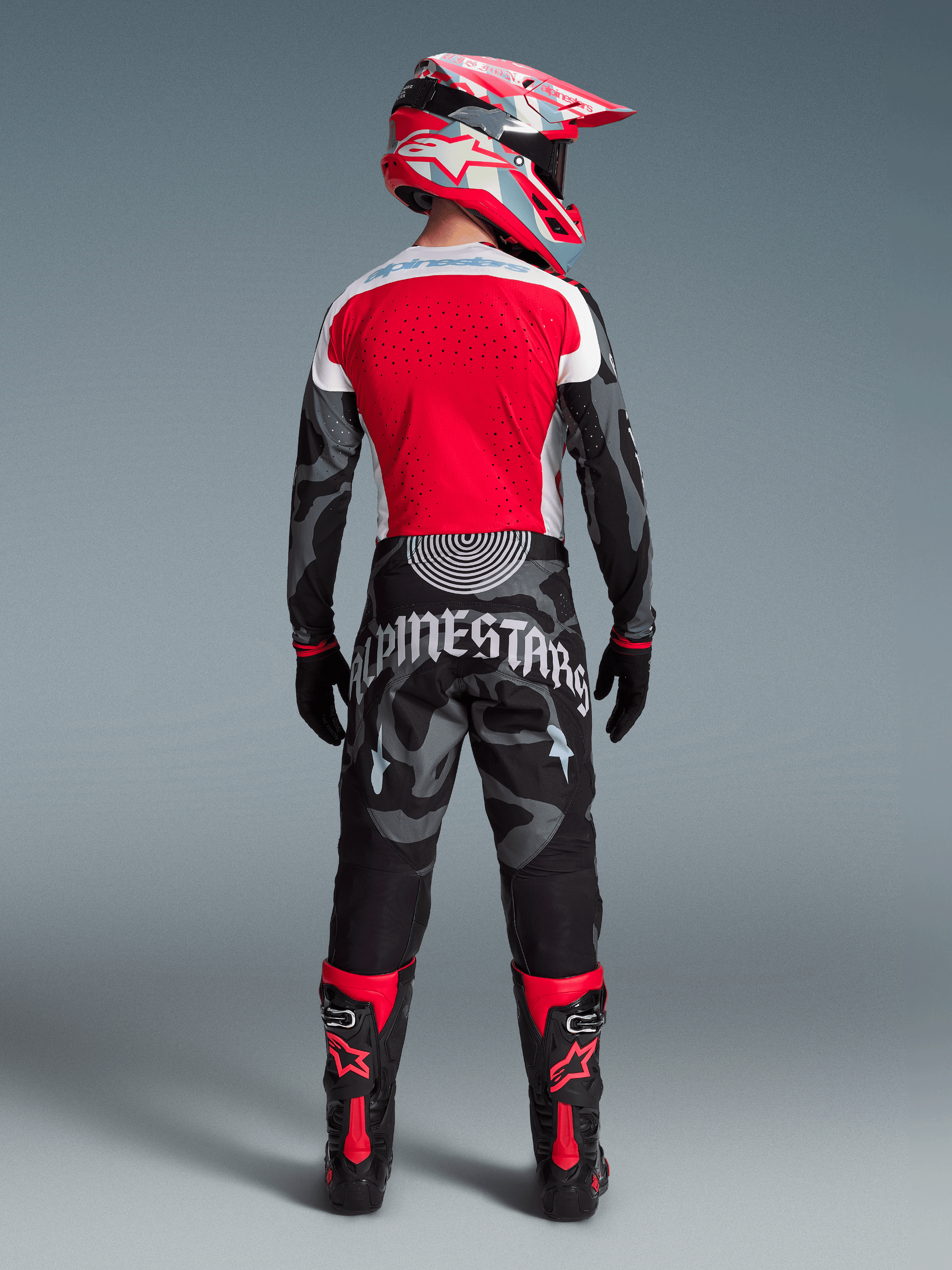Conjunto Techstar Beast Coast Edición Limitada, piloto de espaldas con jersey rojo y pantalones de camuflaje gris y negro.