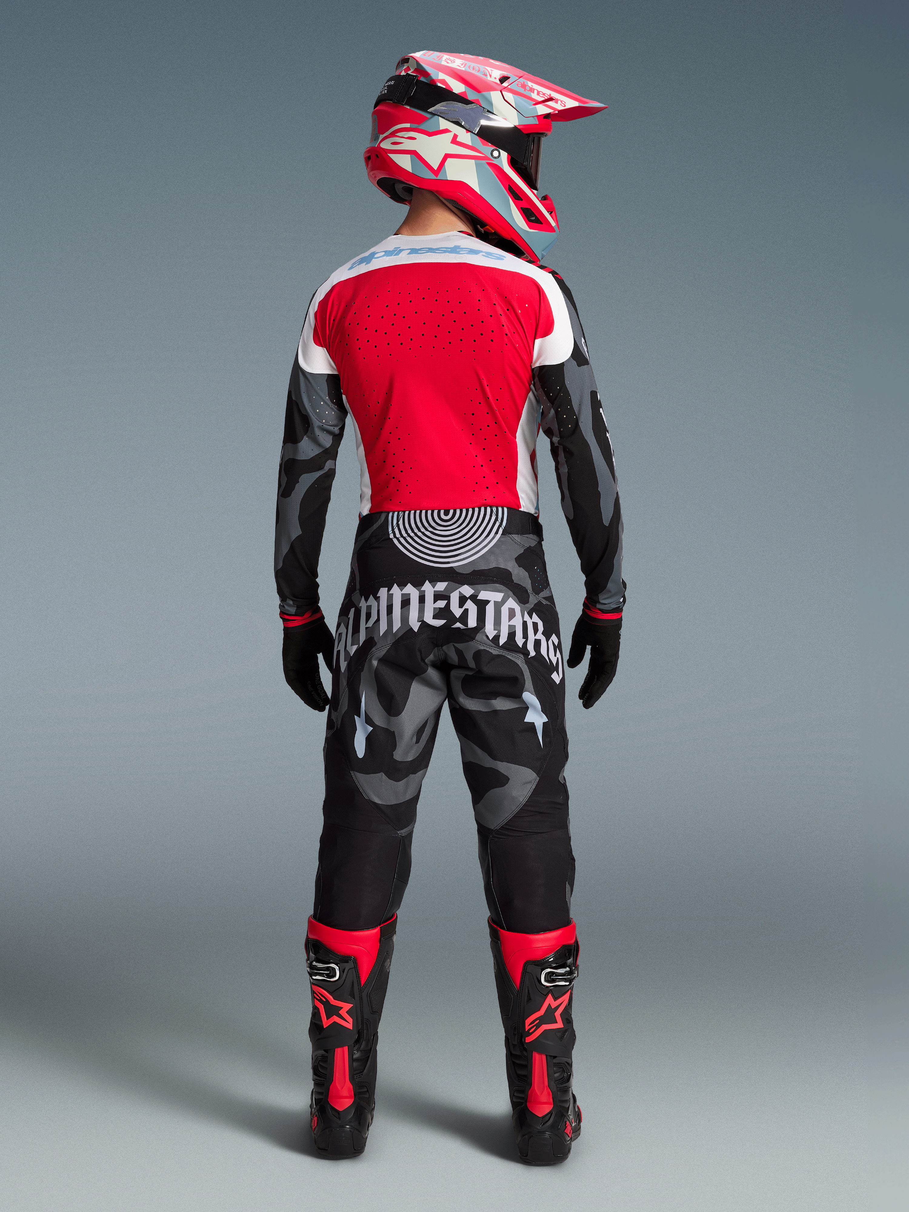 Conjunto Techstar Beast Coast Edición Limitada, piloto de espaldas con pantalones de camuflaje y jersey rojo de motocross.