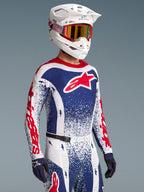 Alpinestars Camiseta Techstar Unity, jersey de motocross azul y blanco con diseño salpicado y detalles rojos, visto en modelo