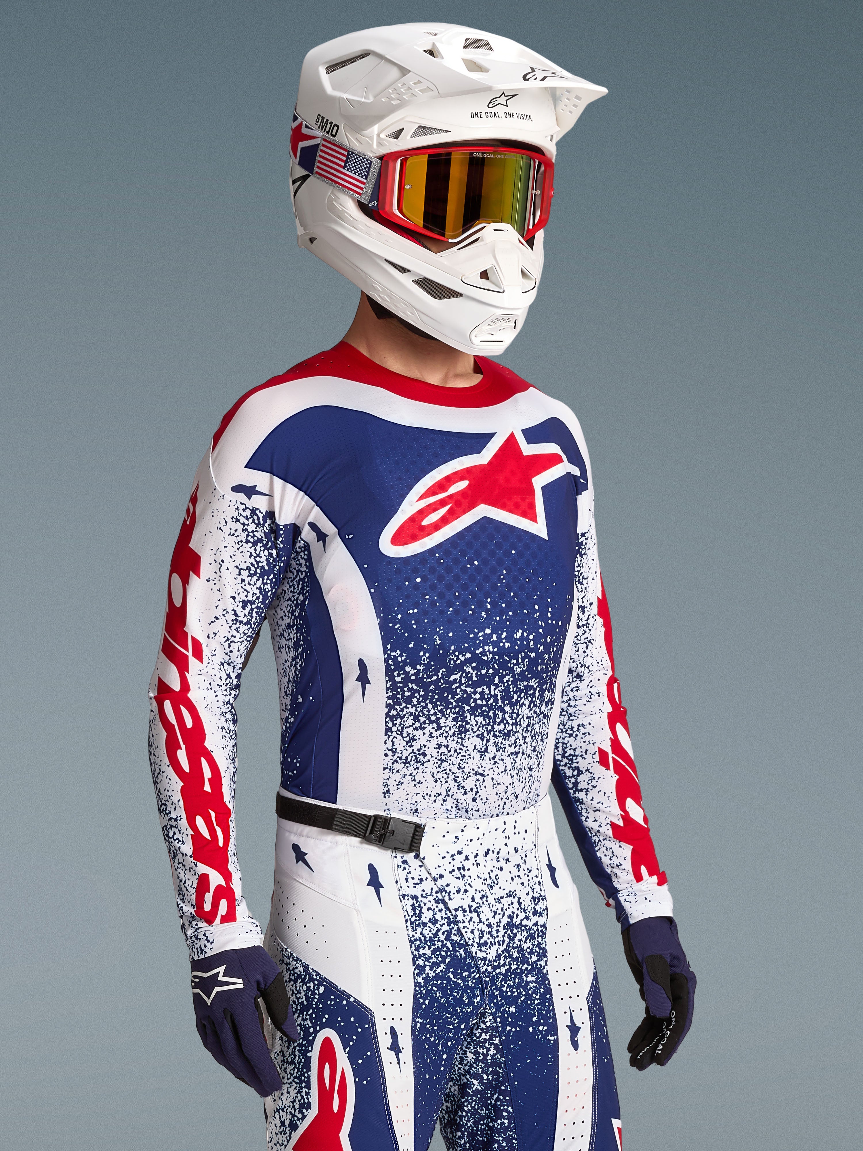 Alpinestars Camiseta Techstar Unity, jersey de motocross azul y blanco con diseño salpicado y detalles rojos, visto en modelo